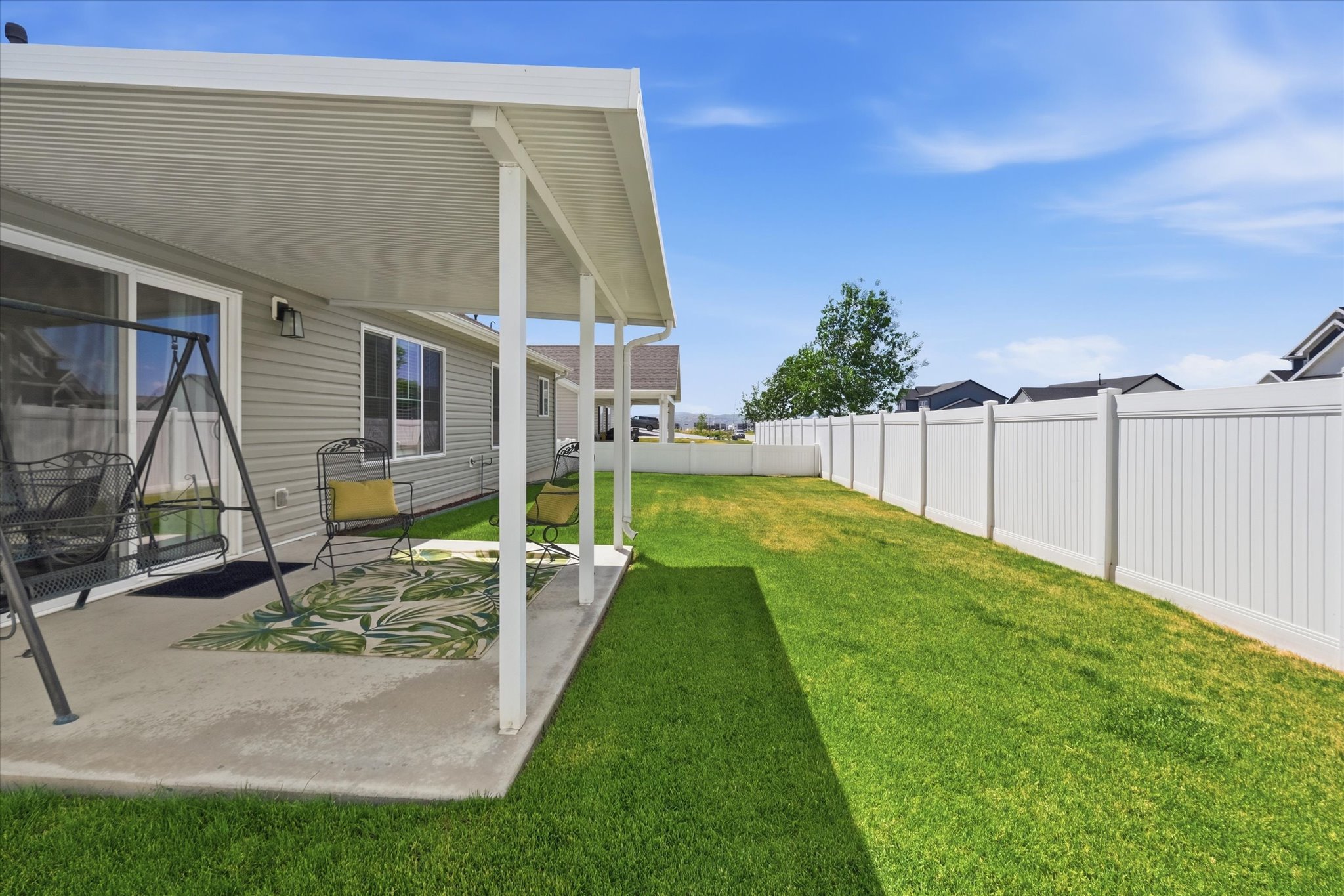 Expansive backyard featuring a concrete patio, a wide aluminum patio cover, a well-maintained lawn, and a tall privacy fence