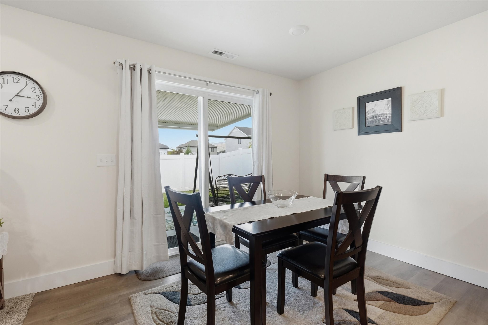 Dining area featuring wood-finish flooring and a sliding glass door with vertical blinds