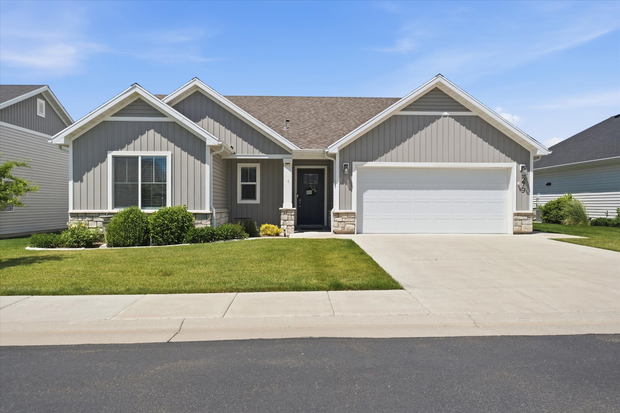 Ranch-style exterior with gray vertical siding and stone accents
