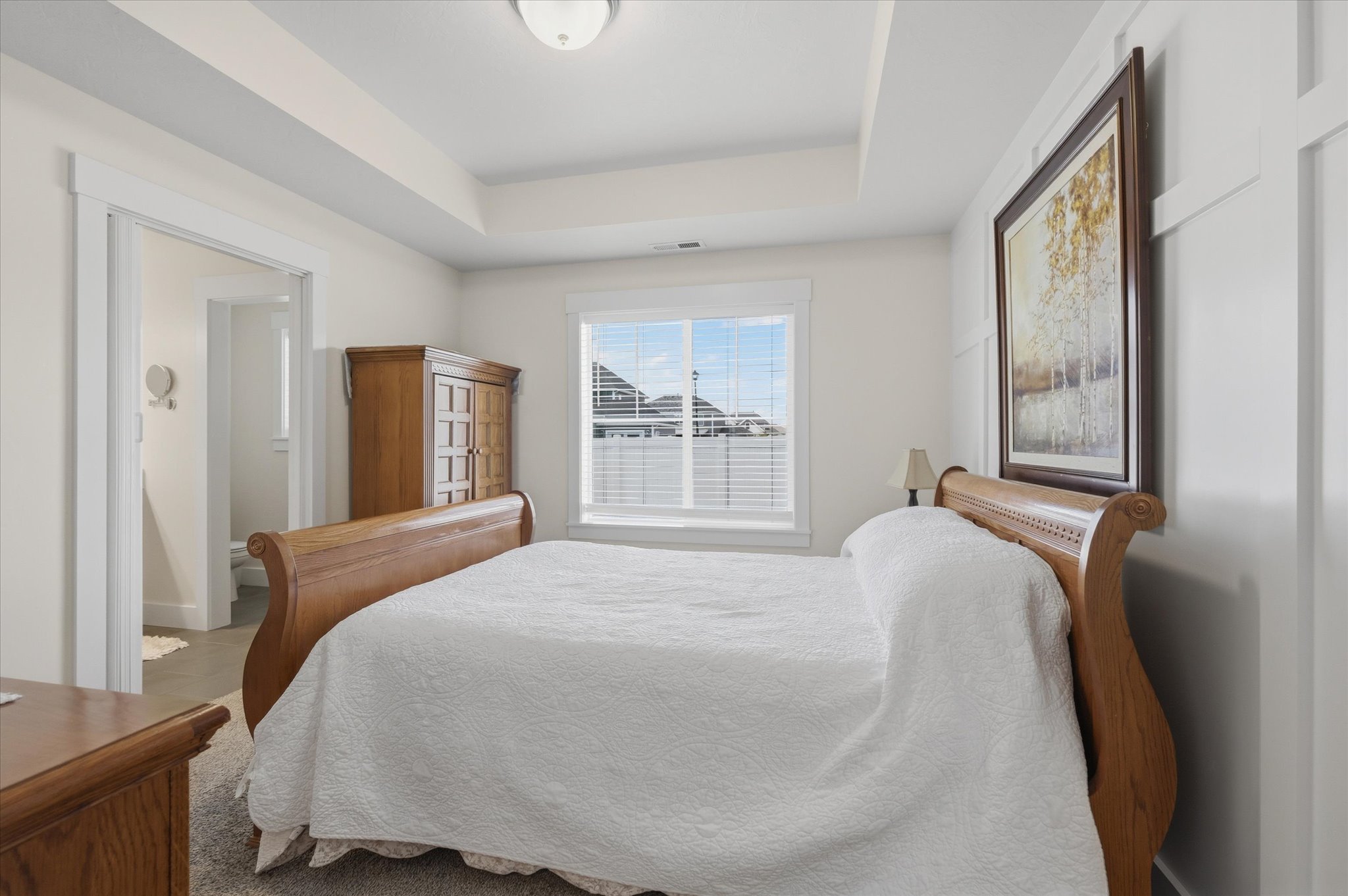 Recessed tray ceiling, neutral wall tones, window with white blinds, white trim, and carpeting