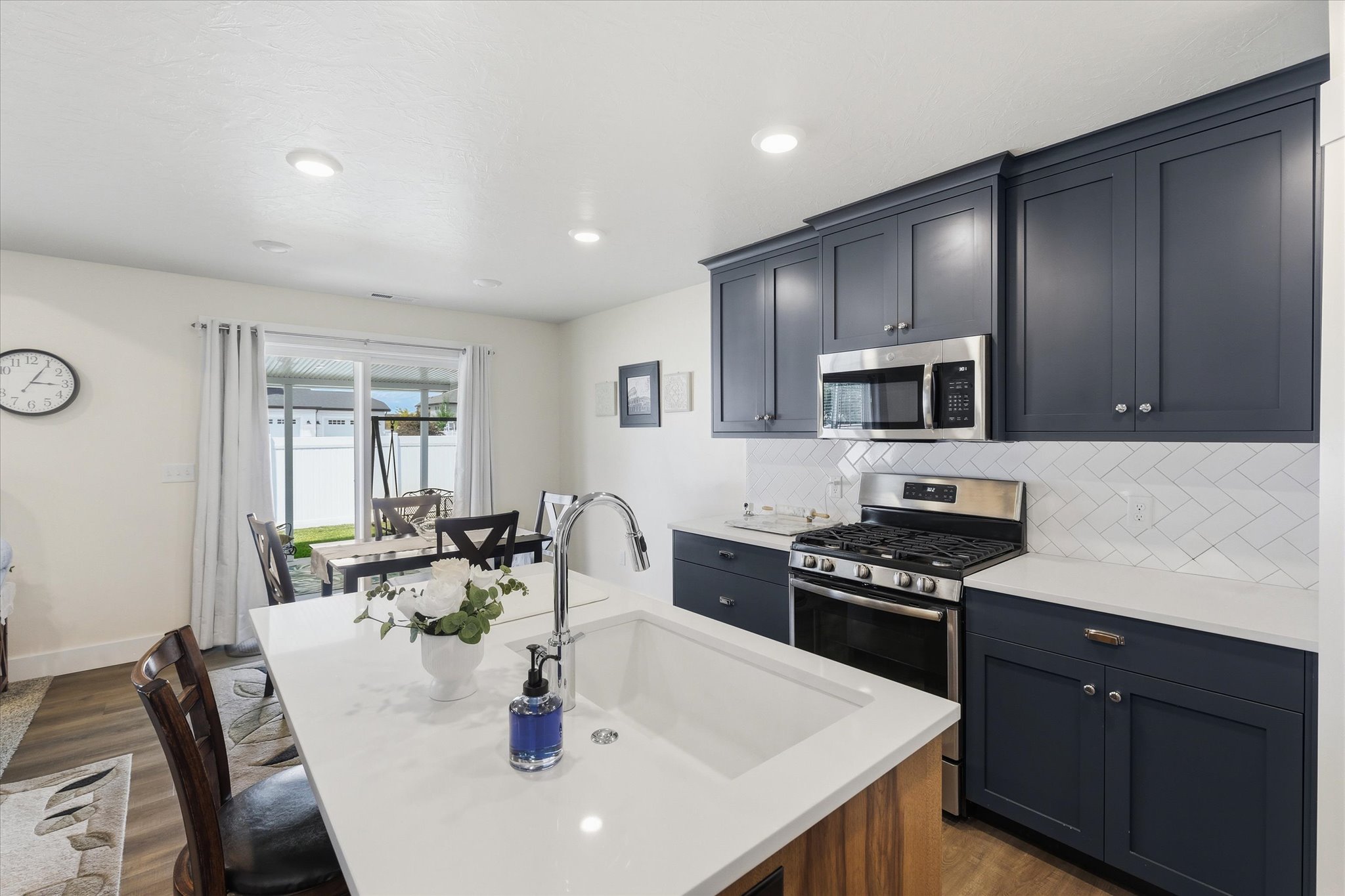 Contemporary kitchen featuring dark blue shaker cabinetry, white countertops, and a white herringbone tile backsplash