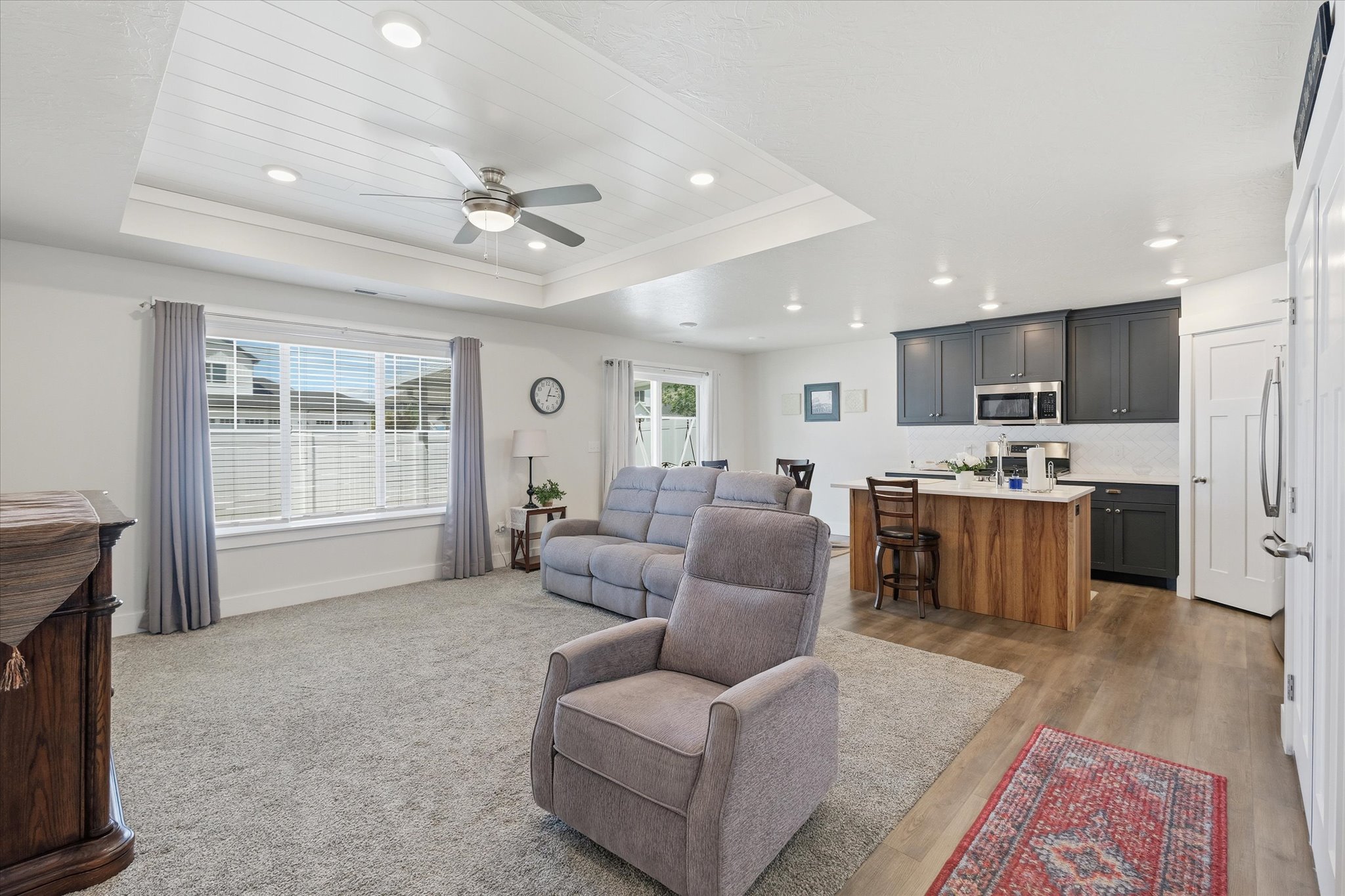 Open-concept living space with a tray ceiling featuring shiplap detailing and recessed lighting