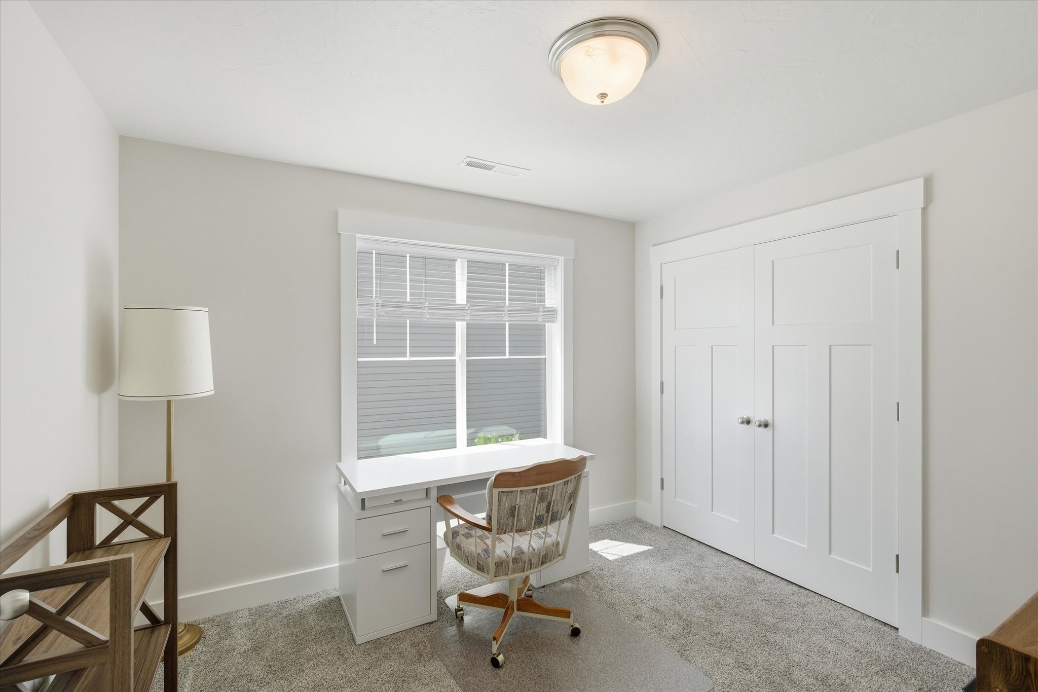 Light-filled room featuring white trim, a double-door closet with panel detailing, and gray patterned carpeting