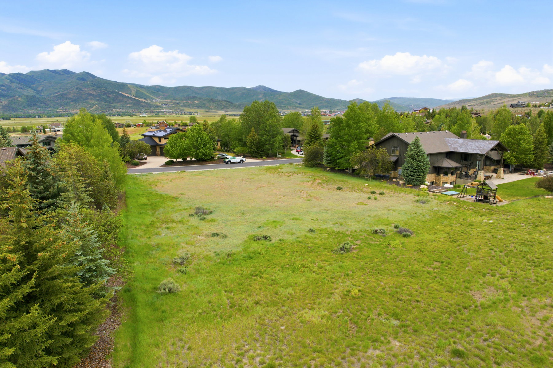 Expansive grassy lot featuring a relatively level grade and scattered natural vegetation