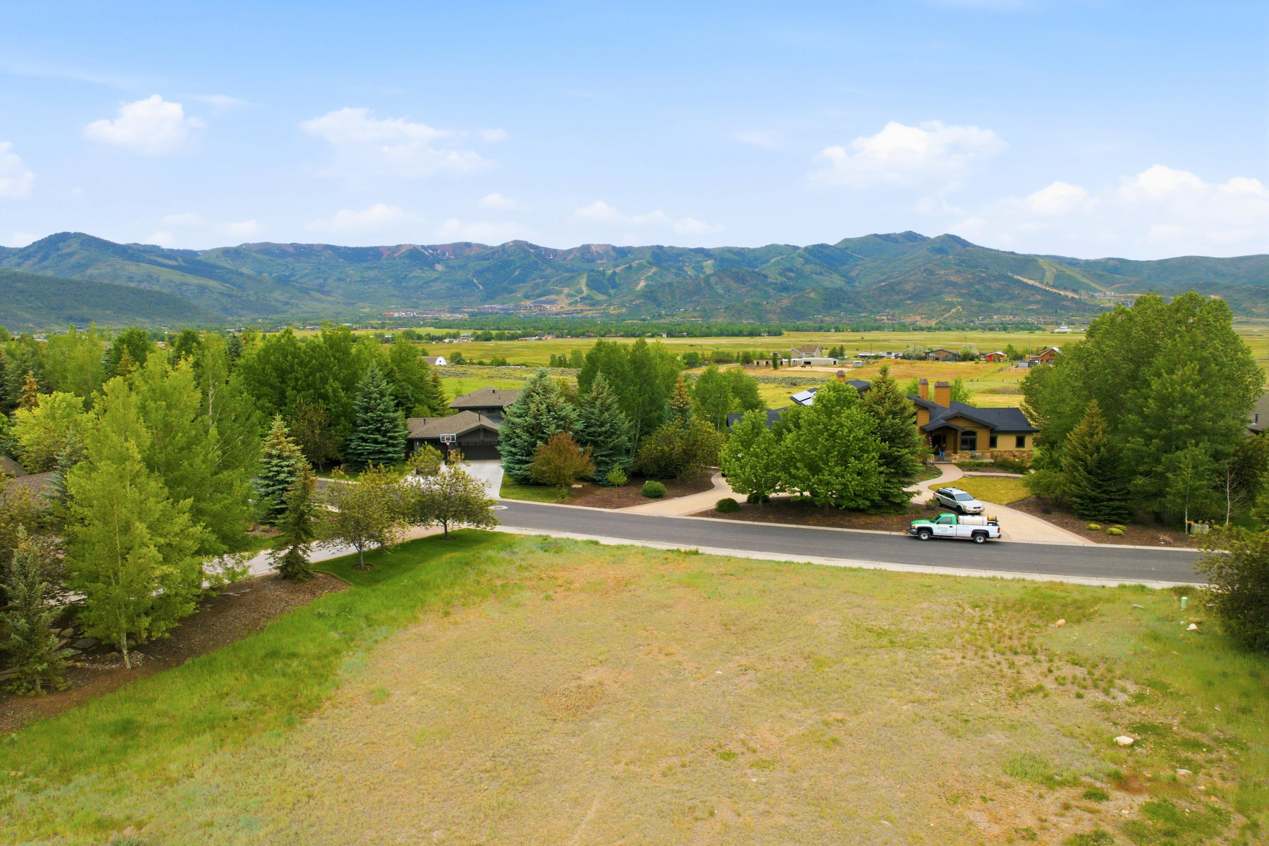 Expansive mountain landscape with a verdant valley, surrounded by mature trees