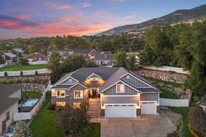 View of front of home featuring board and batten siding, concrete driveway, stone siding, and a gate