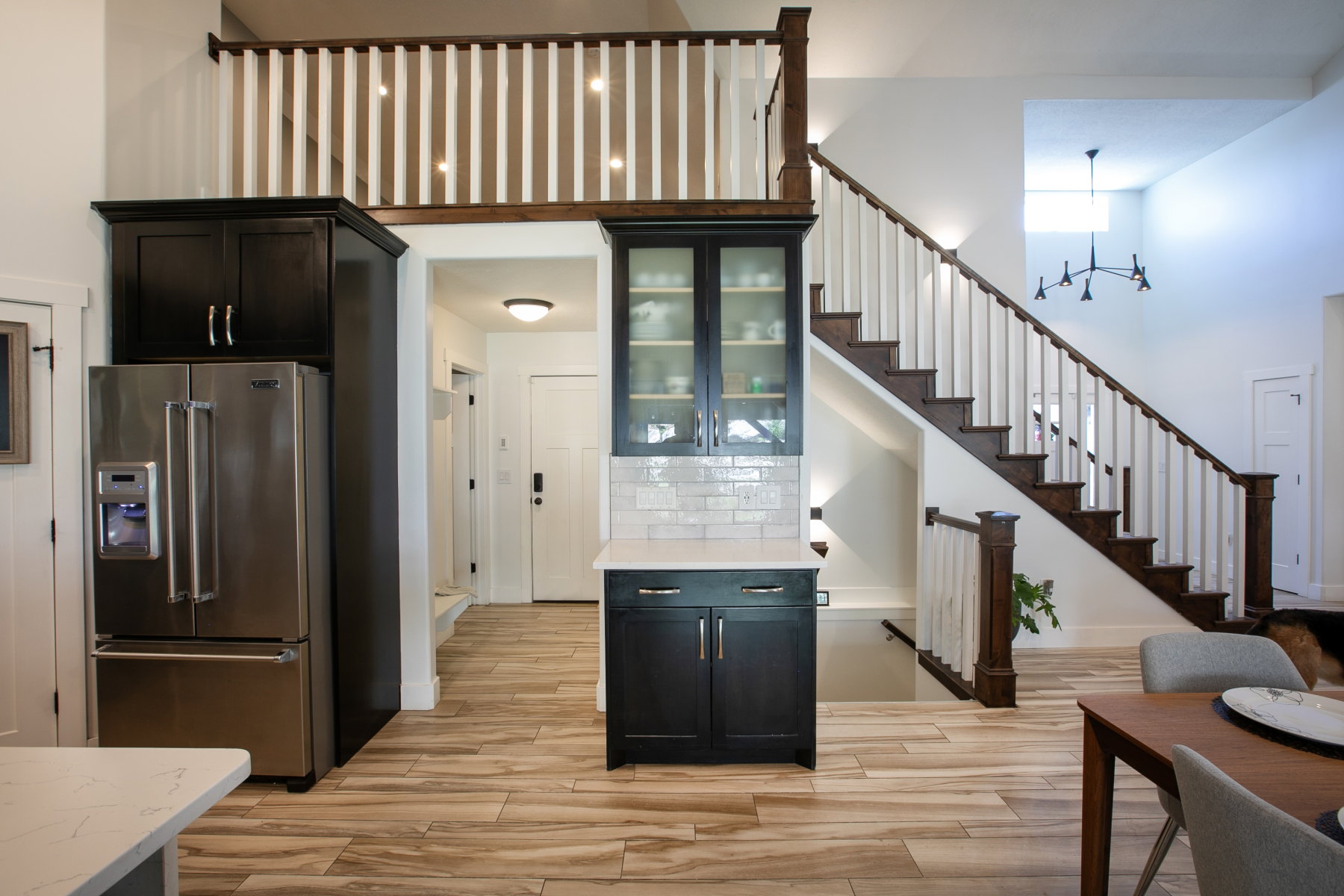 Expansive open-concept space featuring a grand staircase with dark wood-finish treads and white balusters