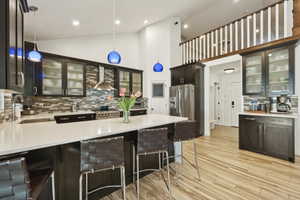 Kitchen featuring glass insert cabinets, tasteful backsplash, a peninsula, light stone countertops, and high end appliances