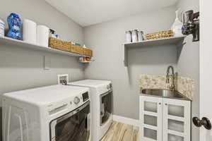 Laundry room with washer and dryer, light wood finished floors, and a textured ceiling