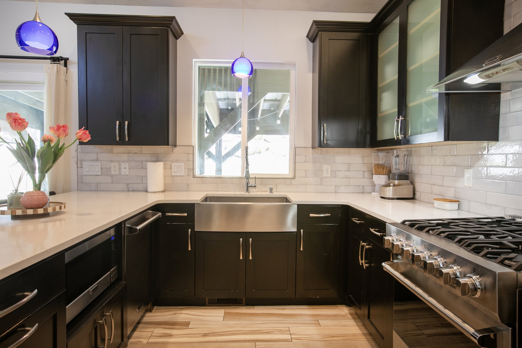 Contemporary kitchen featuring dark cabinetry, light-toned countertops, and a subway tile backsplash