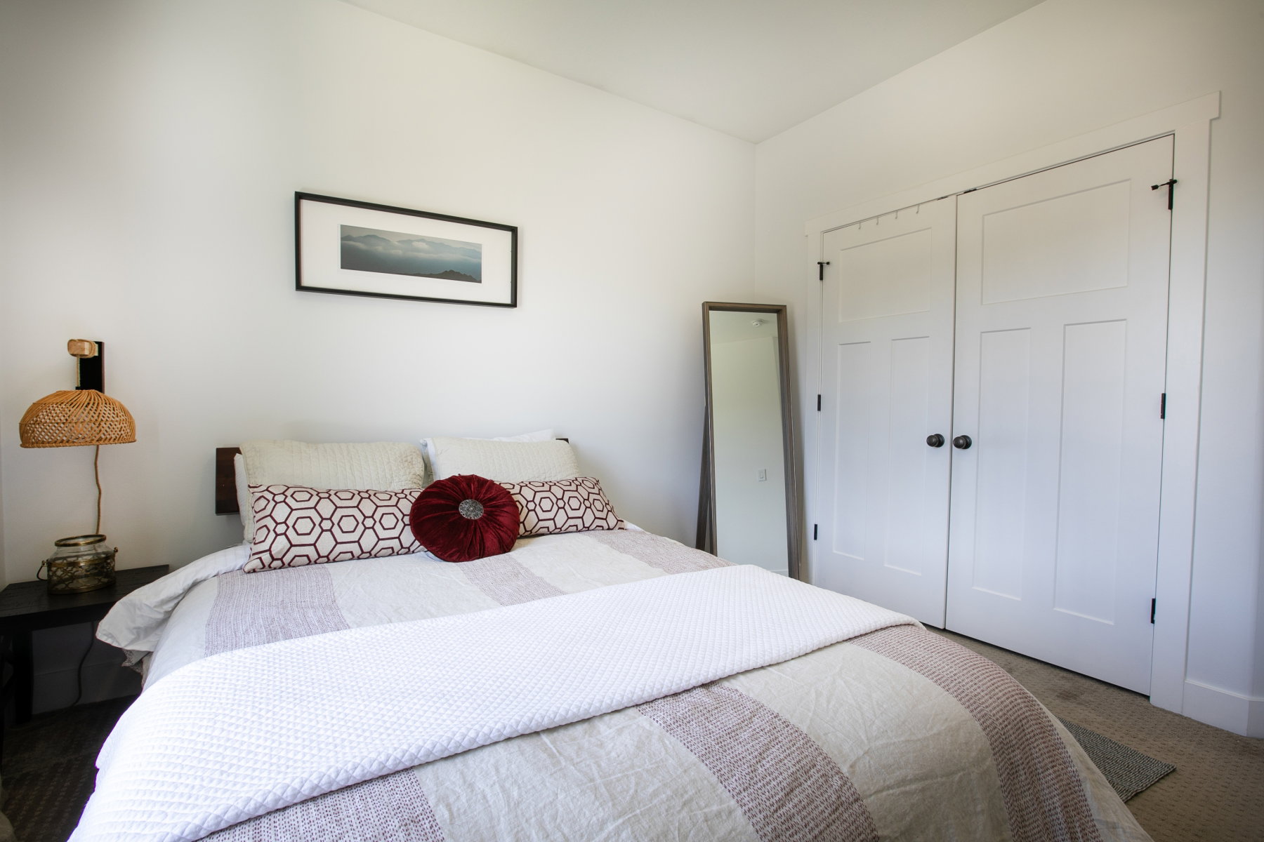 Bedroom featuring white walls, wood-finish flooring, and white bi-fold closet doors with black hardware