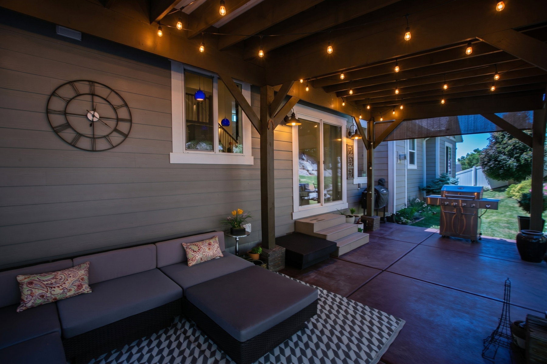 Covered patio featuring a wood beam pergola with string lights, concrete flooring, and direct access to the interior via a sliding glass door