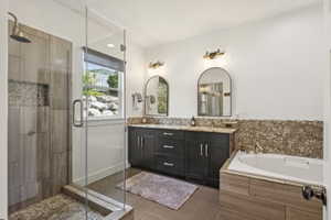 Full bathroom featuring double vanity, a bath, a shower stall, and dark tile patterned floors