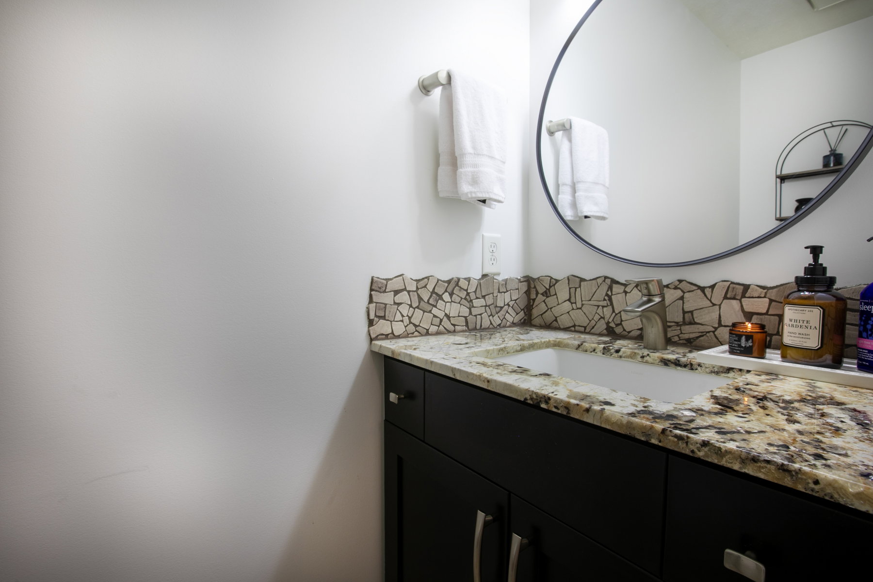 Vanity with a granite countertop, undermount sink, and black cabinetry