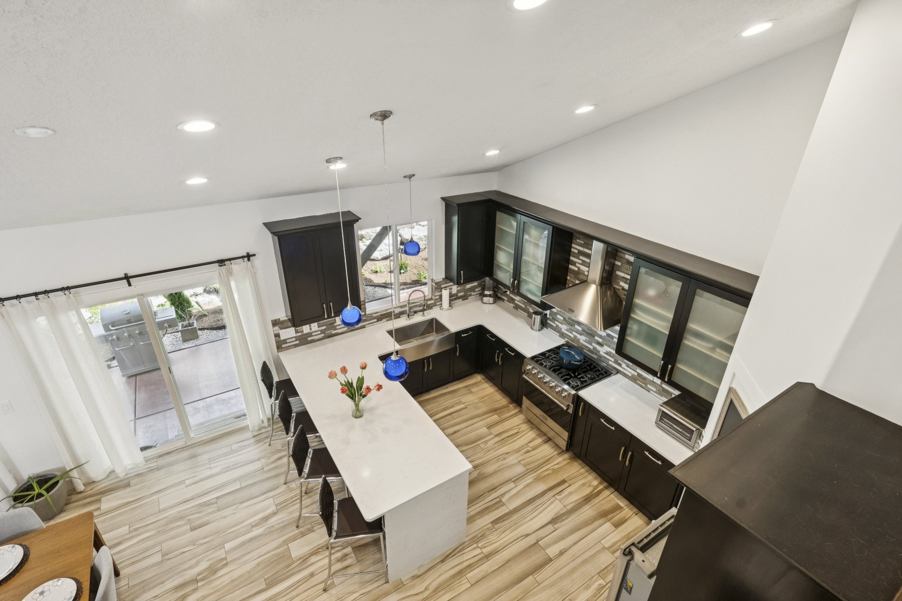 Kitchen featuring dark cabinetry, decorative light fixtures, a kitchen breakfast bar, high end range, and a peninsula