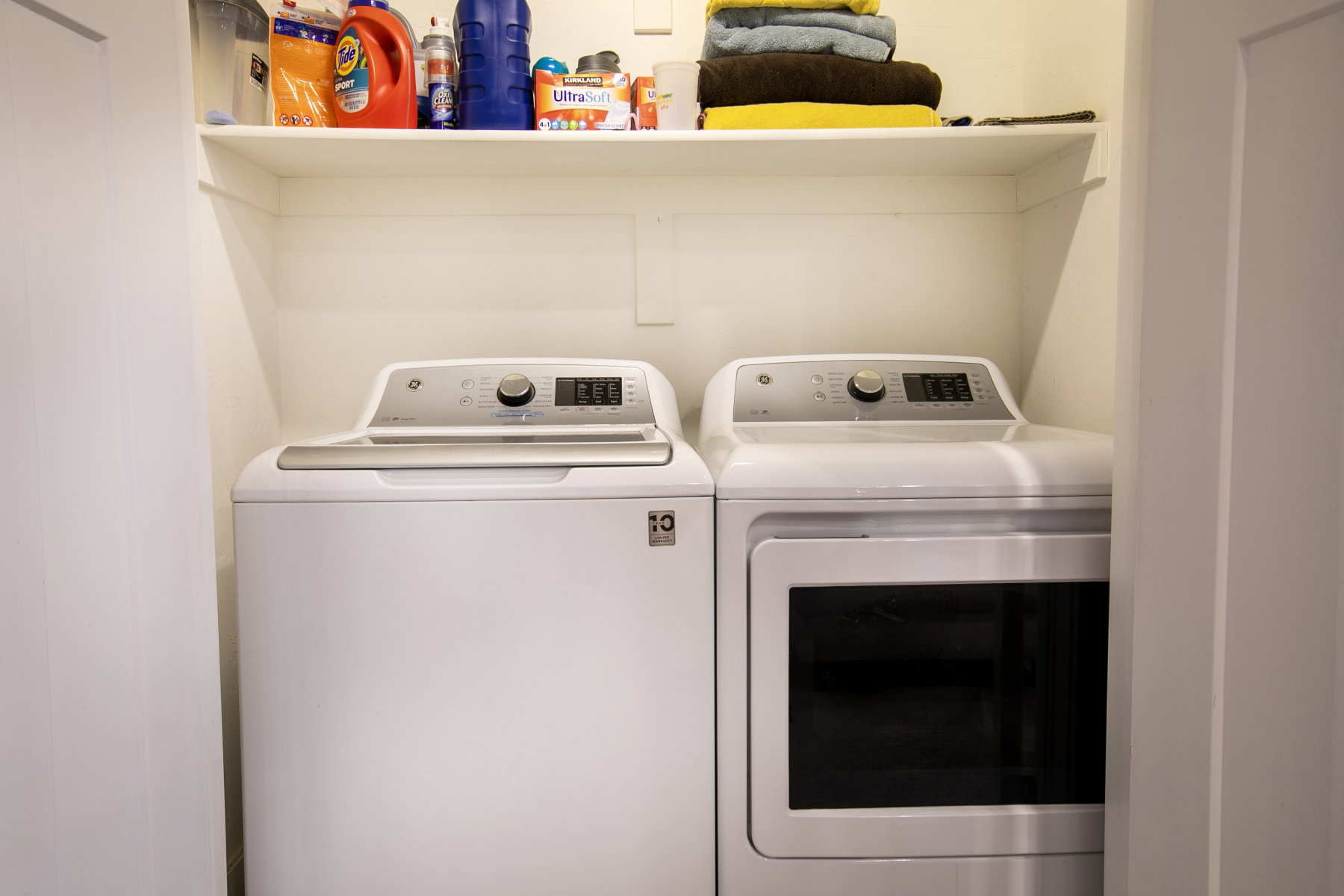 Dedicated laundry closet featuring a white top-load washing machine and a white front-load dryer