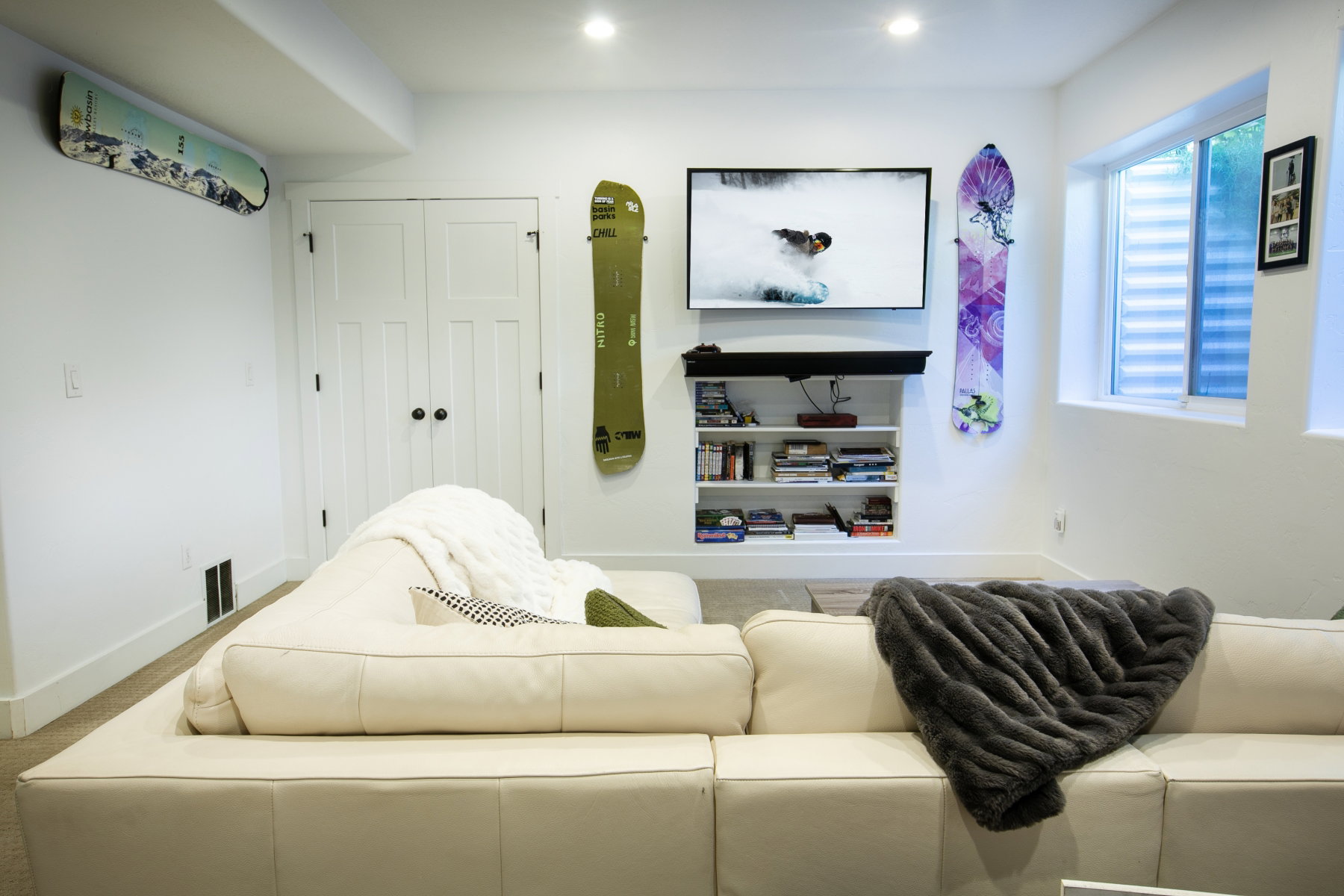 Recessed lighting illuminates this bright space featuring a wall-mounted television above built-in shelving