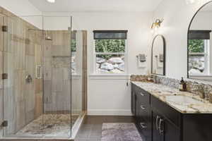 Bathroom featuring double vanity, a shower stall, and dark tile patterned floors