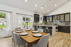 Dining area with vaulted ceiling, light wood finished floors, recessed lighting, and plenty of natural light