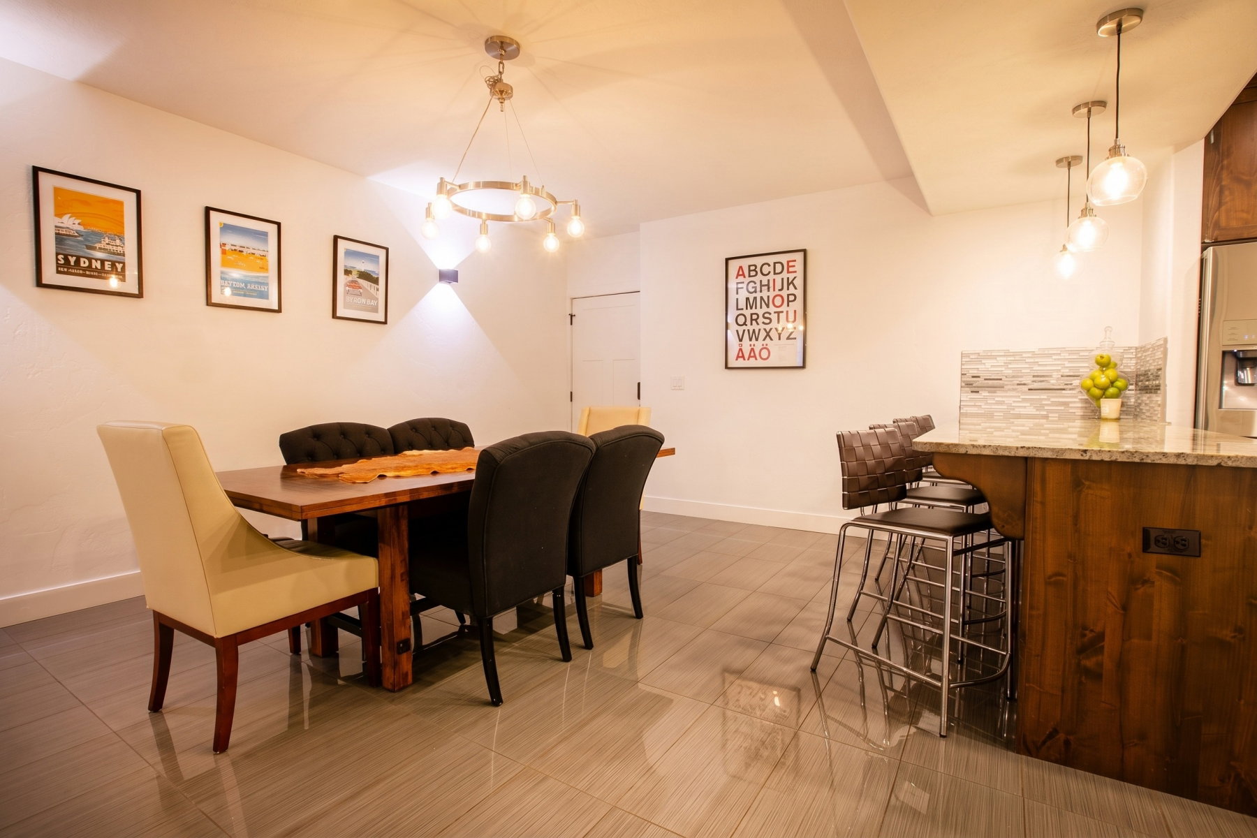 Open-concept dining area featuring tile flooring, a contemporary chandelier, and a wood-finish dining table