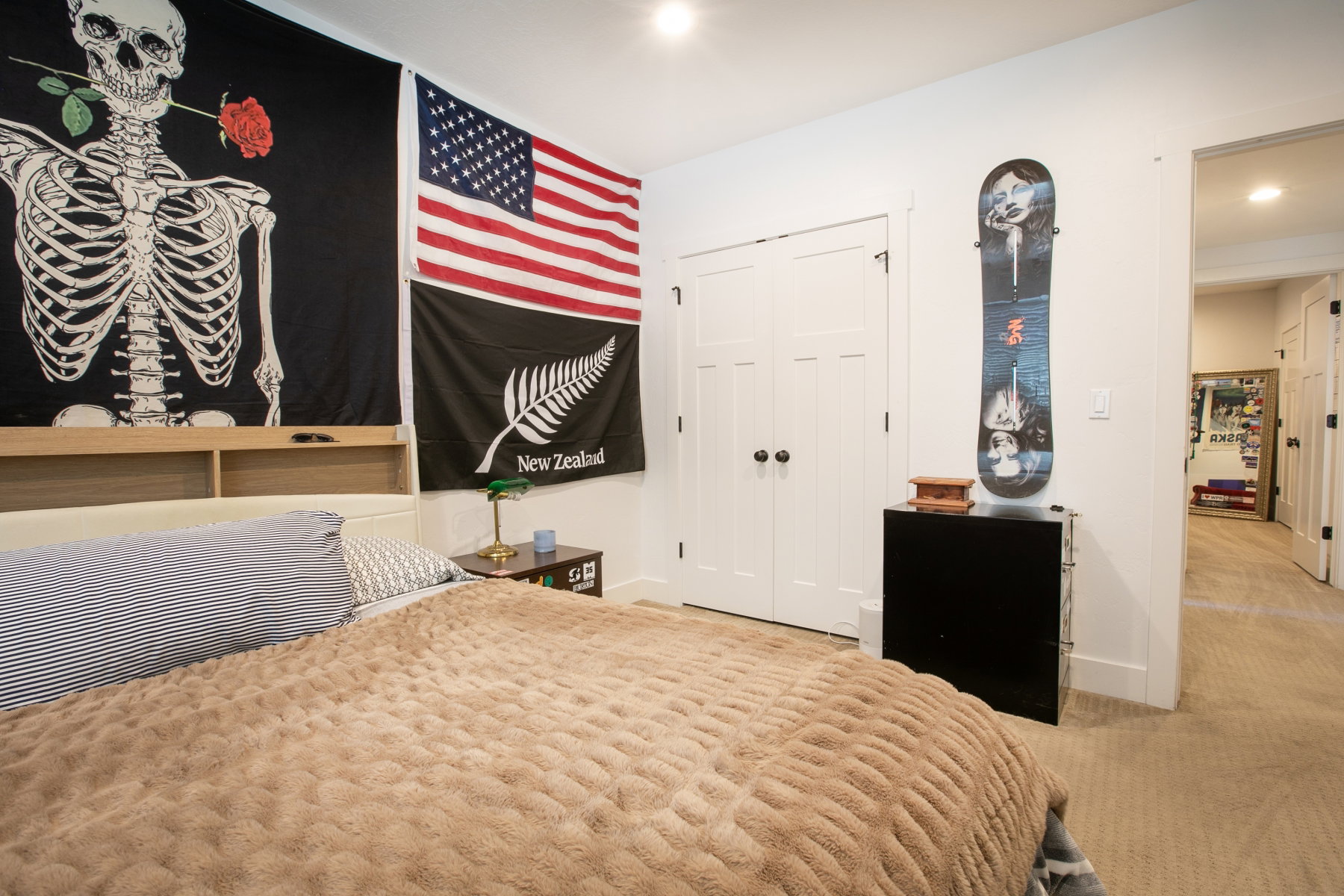 Bedroom featuring a built-in headboard with integrated shelving, recessed lighting, white panel doors with dark hardware, and neutral wall-to-wall carpeting
