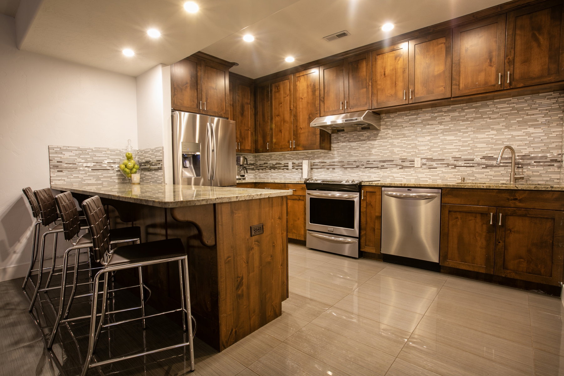 Kitchen featuring wood cabinetry, stainless steel appliances, a tile backsplash, light-toned countertops, and recessed lighting