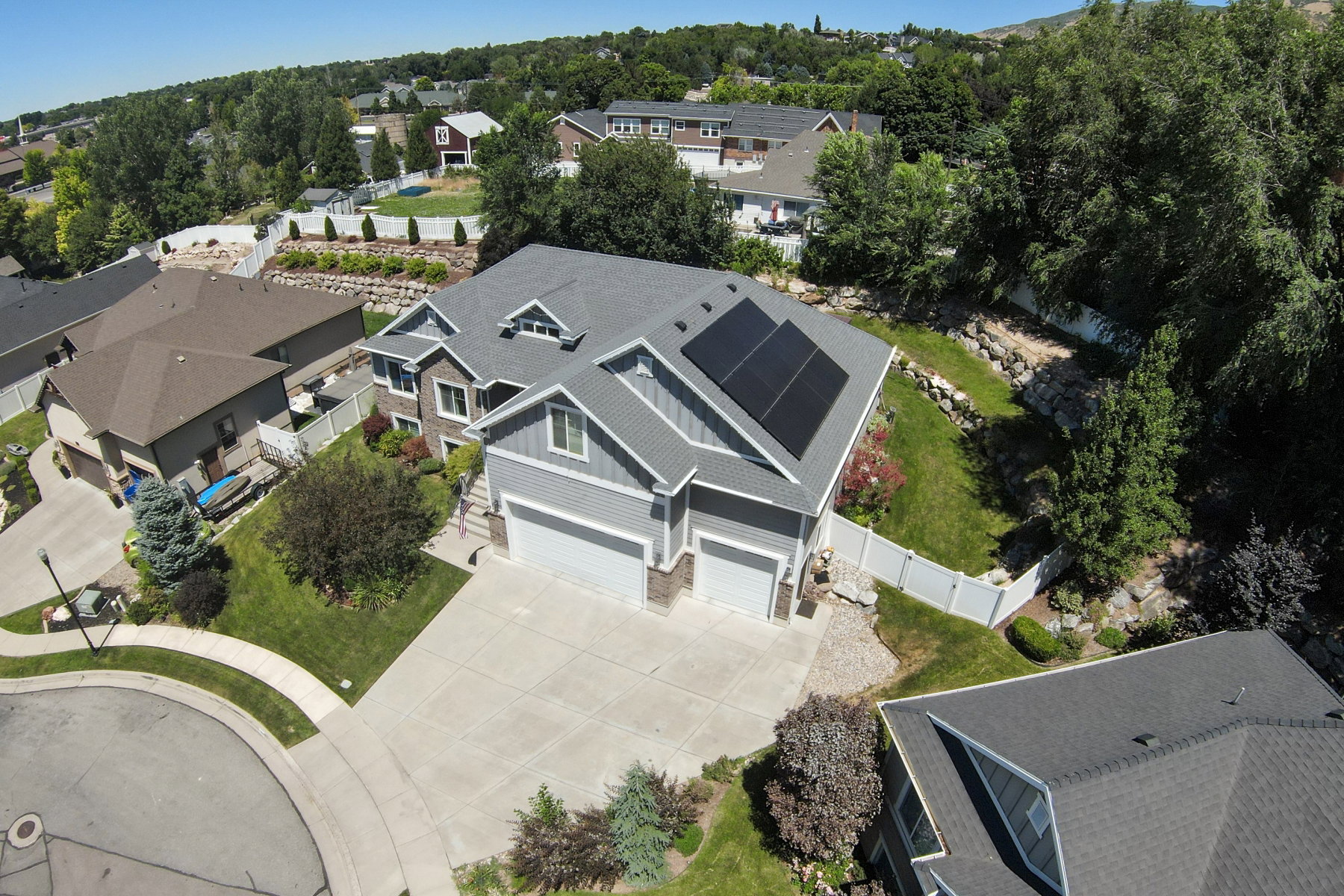 Gray two-story residence featuring a two-car garage, solar panels, and a concrete driveway