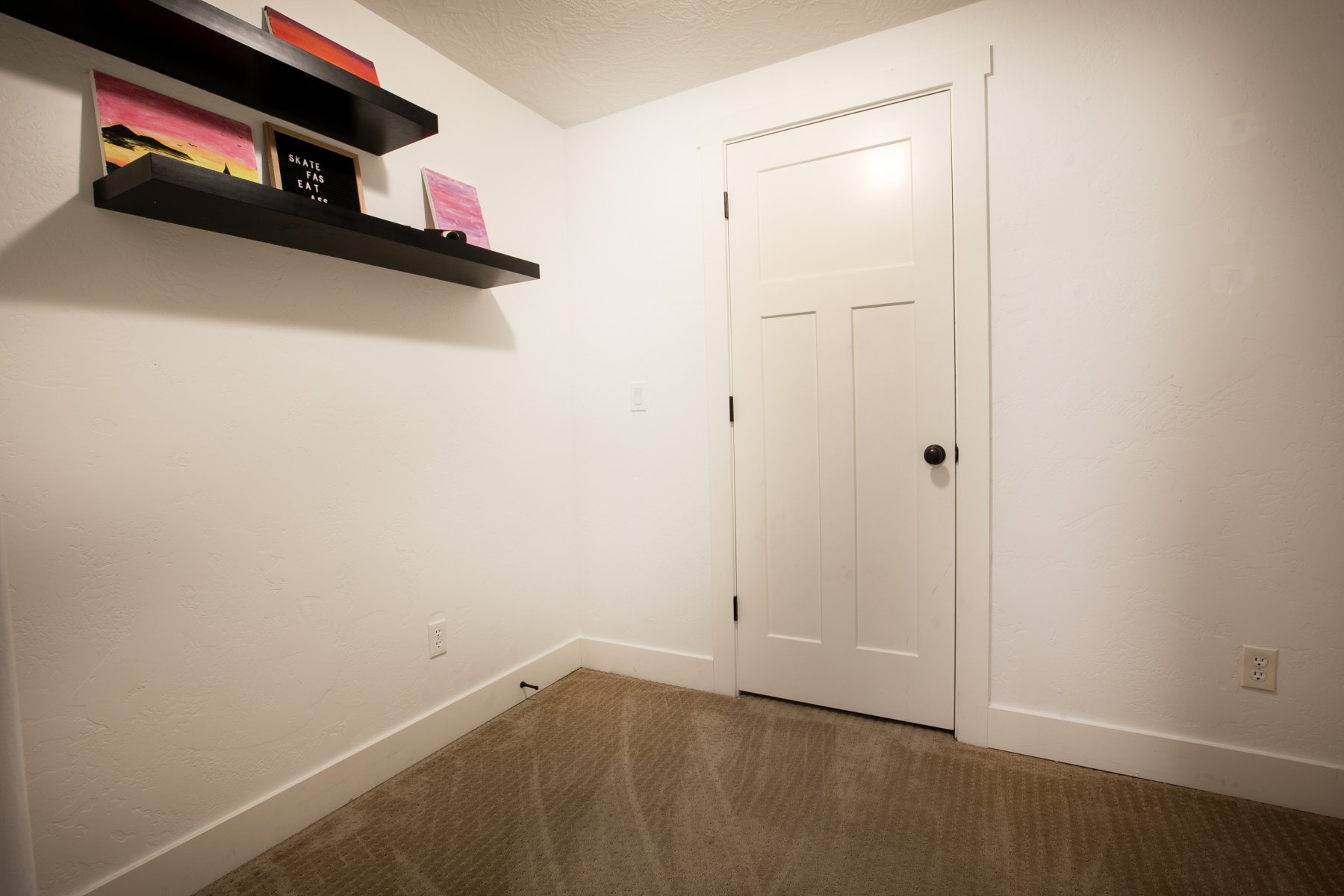 White paneled interior door with matte black hardware, set within a neutral-toned room