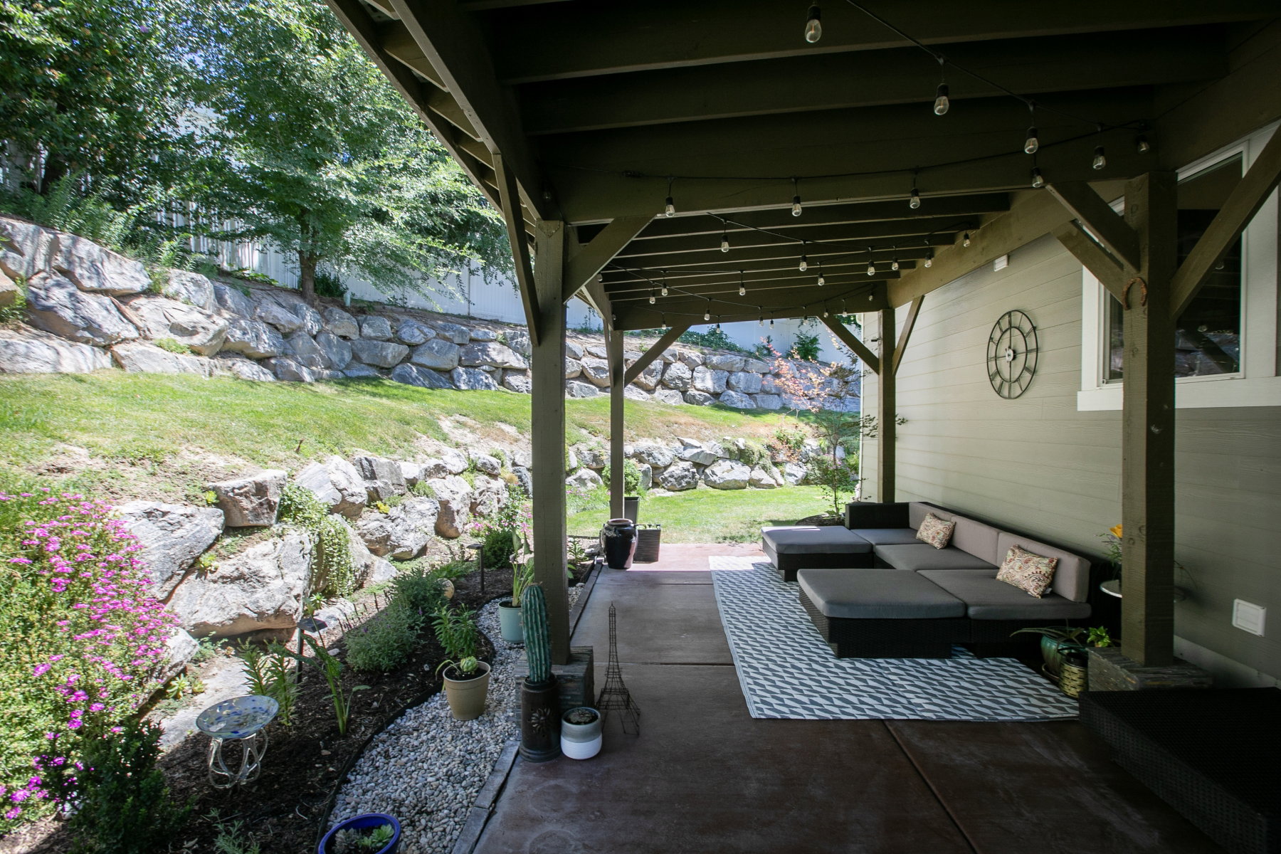 Covered outdoor patio with a concrete surface, supported by exposed wood beams