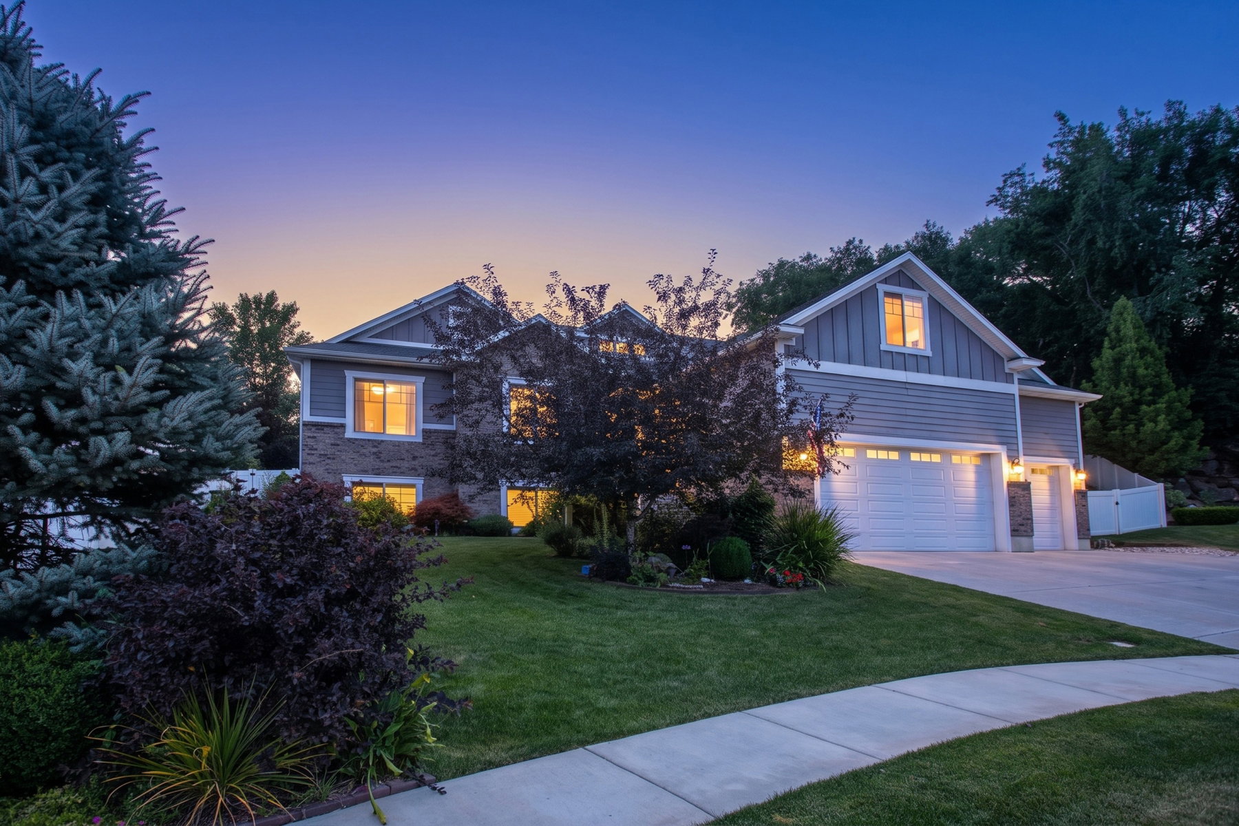 Contemporary exterior featuring mixed material siding, a two-car garage, mature landscaping, and a concrete driveway