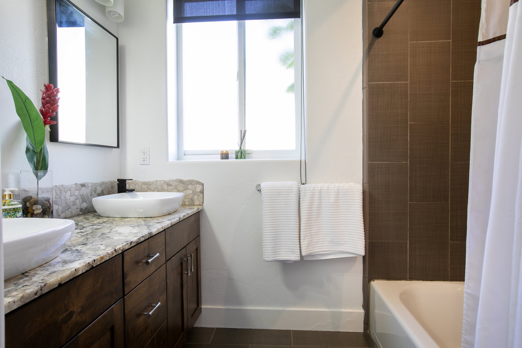 Bathroom featuring dual vessel sinks set on a granite-topped vanity with dark wood-finish cabinetry