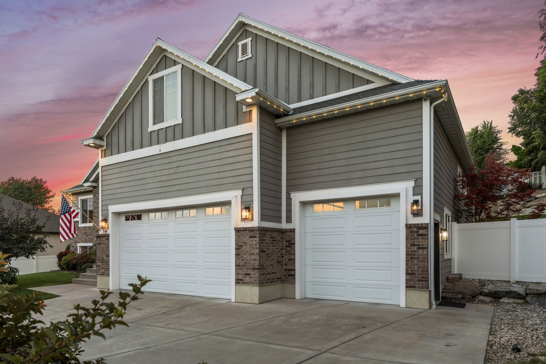 View of front of house with board and batten siding, driveway, a garage, and brick siding
