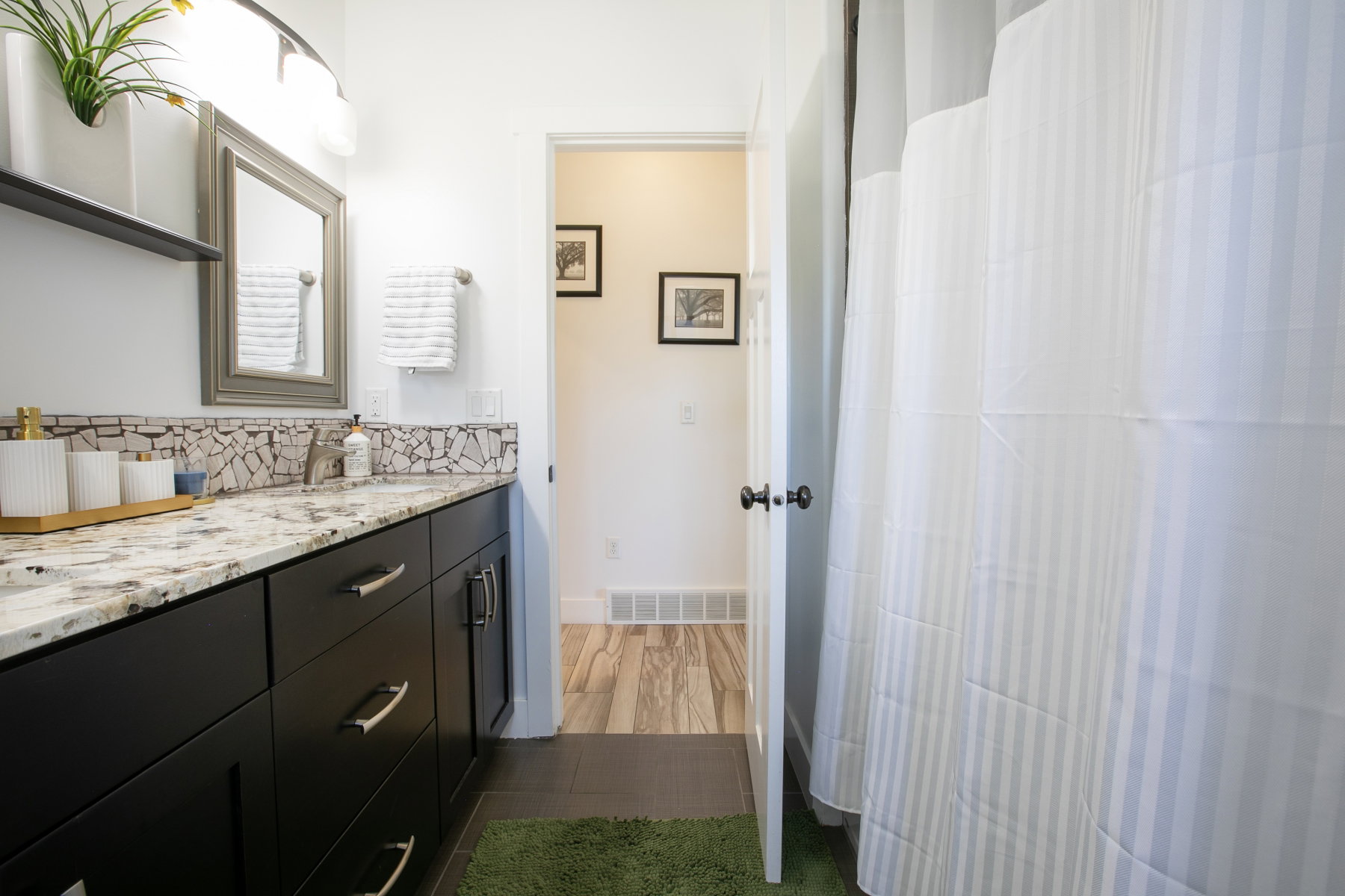 Bathroom vanity featuring dark wood cabinetry with brushed nickel hardware, a speckled countertop, and a mosaic tile backsplash