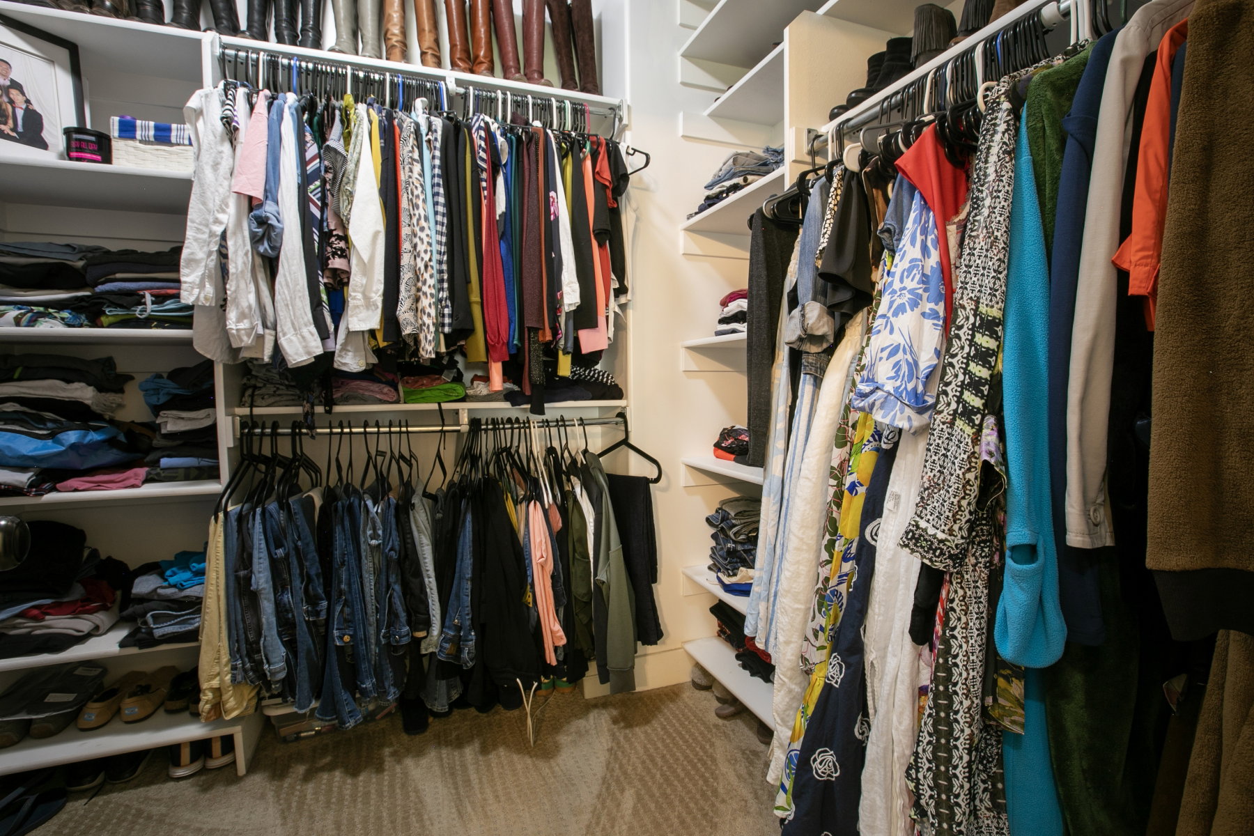 Expansive walk-in closet featuring built-in shelving, multiple hanging rods, and a neutral carpet