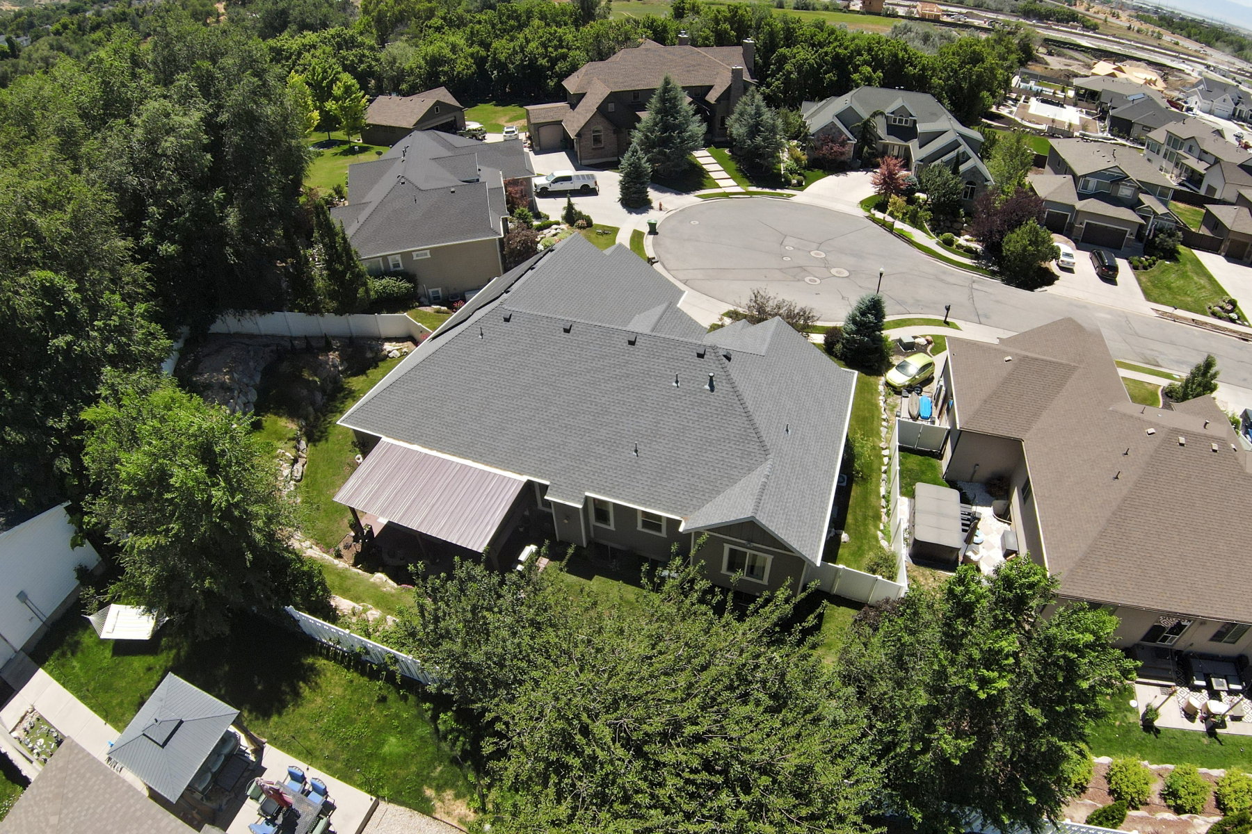 Residential property featuring a dark grey shingle roof, light grey siding, and an attached covered patio with a metal roof