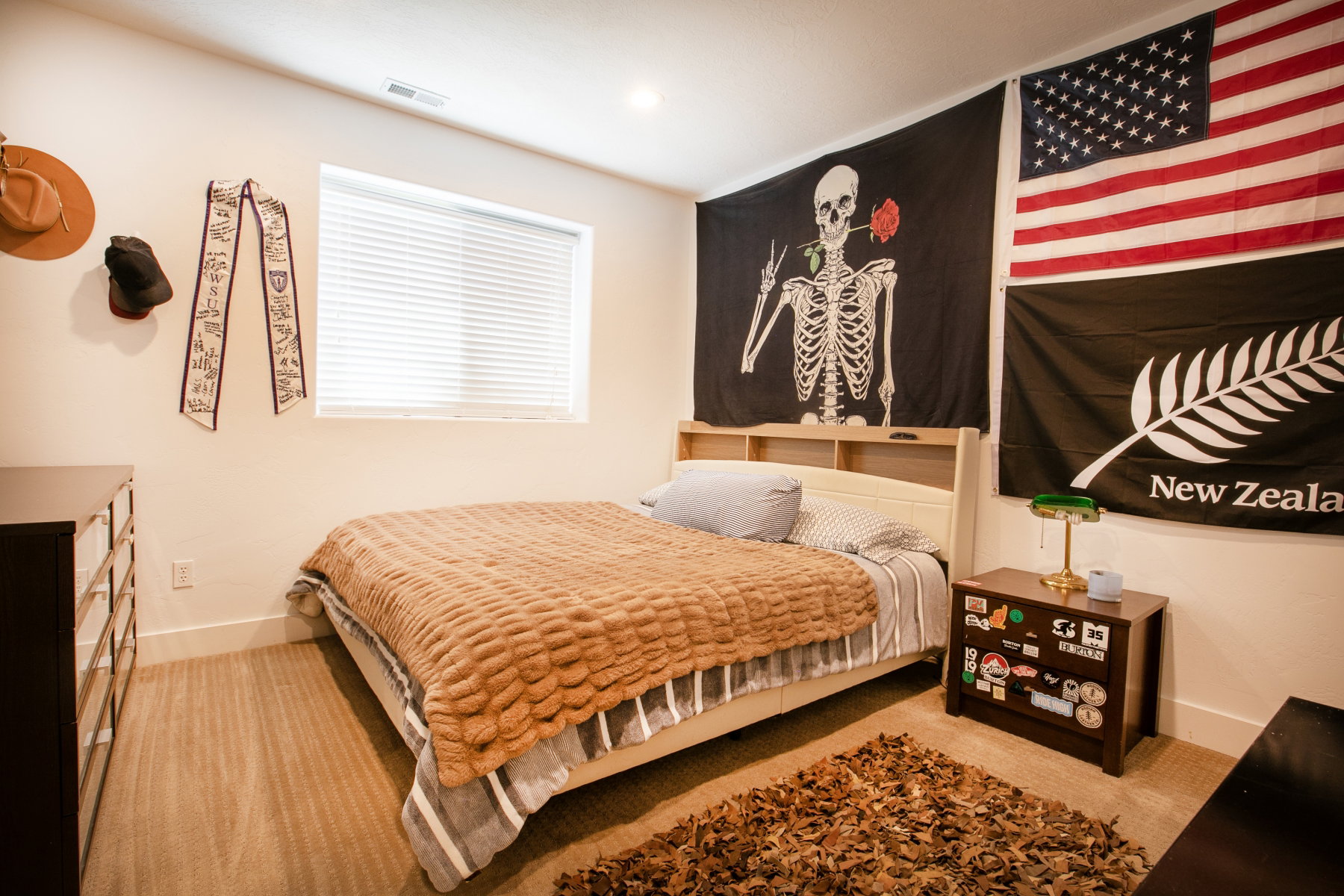 Carpeted room featuring a window with horizontal blinds, overhead recessed lighting, and a light-toned bed frame with an integrated headboard shelf