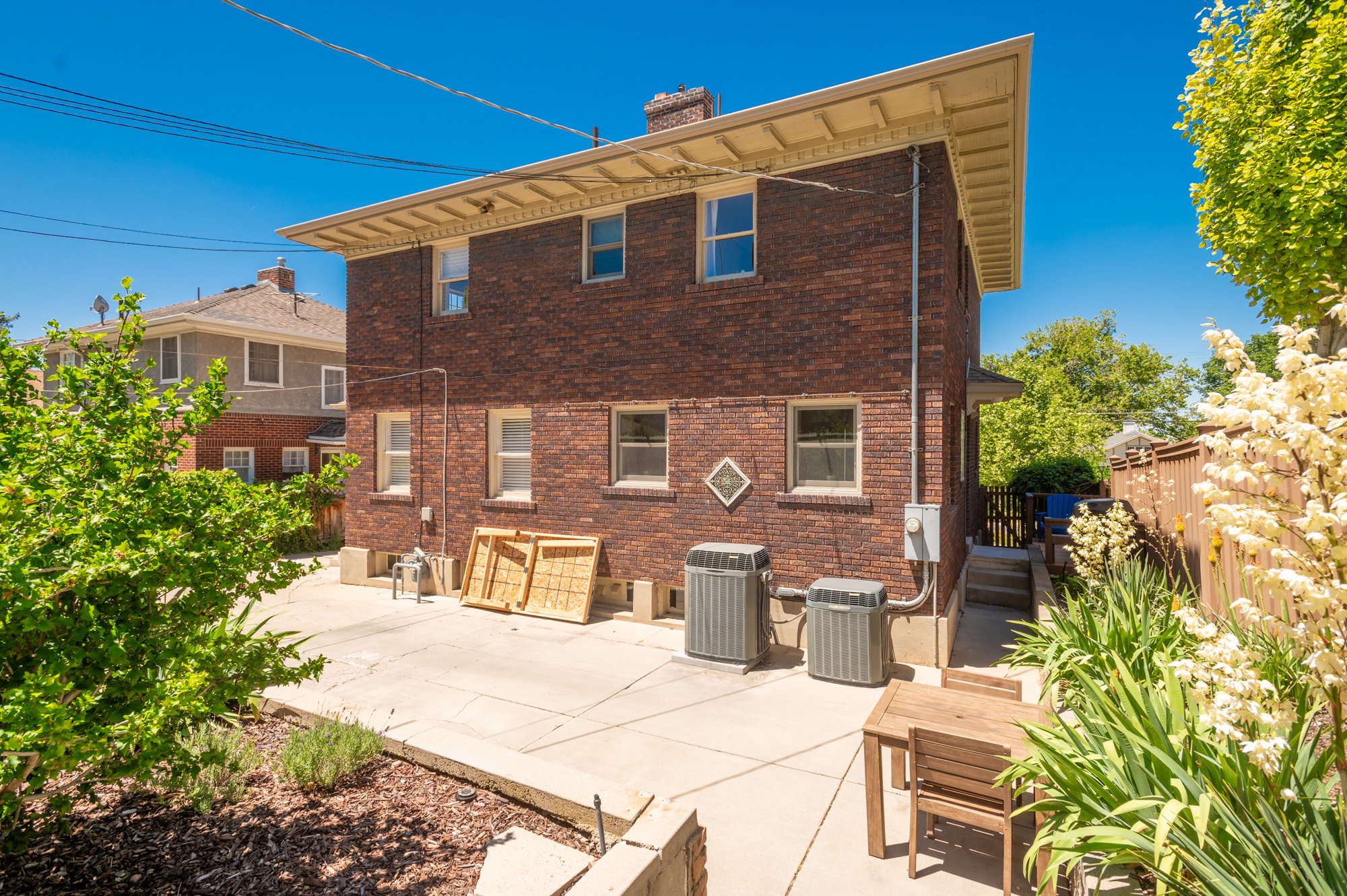 Brick exterior featuring a concrete patio, established landscaping, and a wooden privacy fence