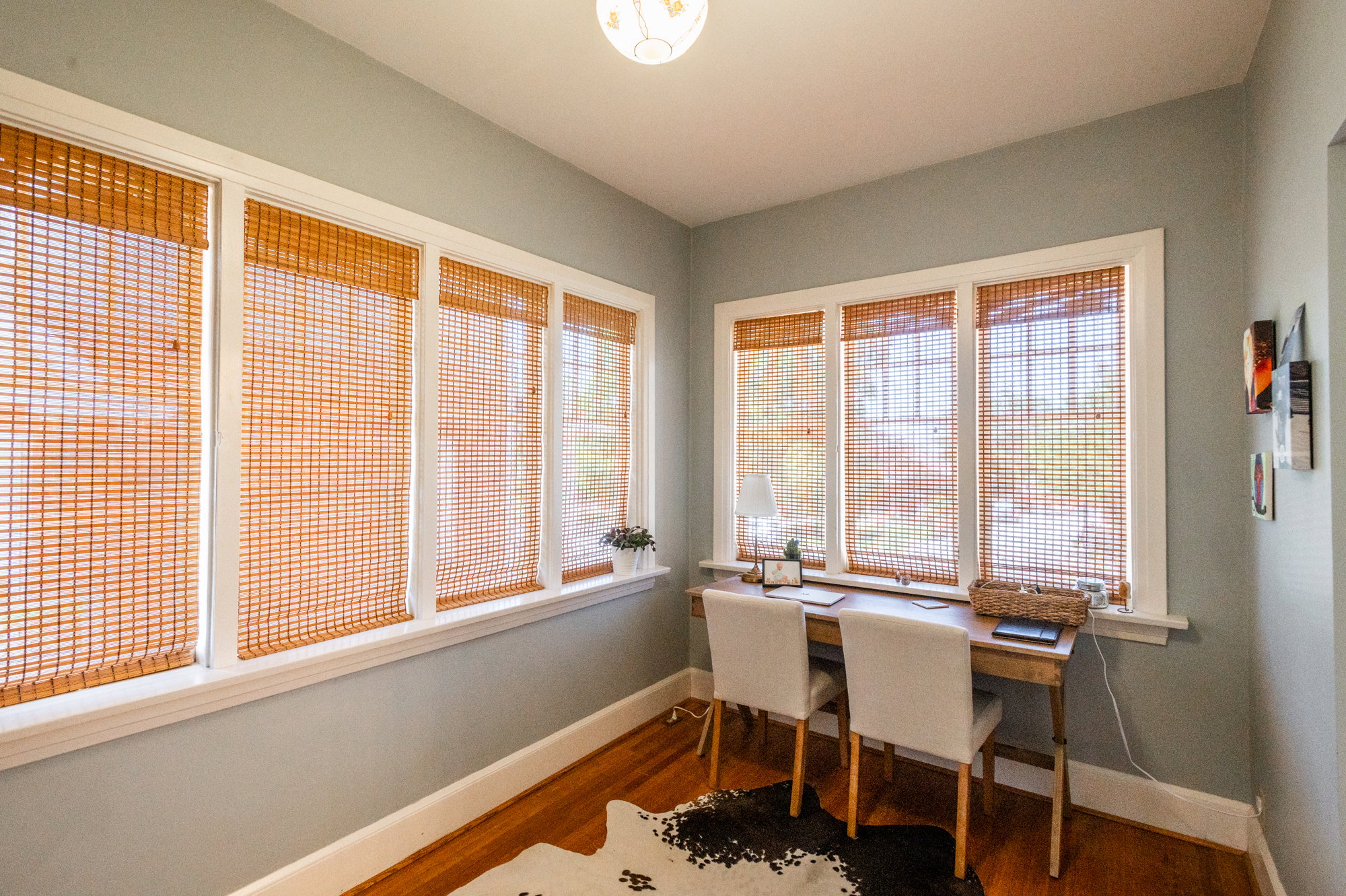 Bright room featuring multiple windows with natural wood blinds, hardwood flooring, light gray wall paint, white trim, and a semi-flush mount ceiling light