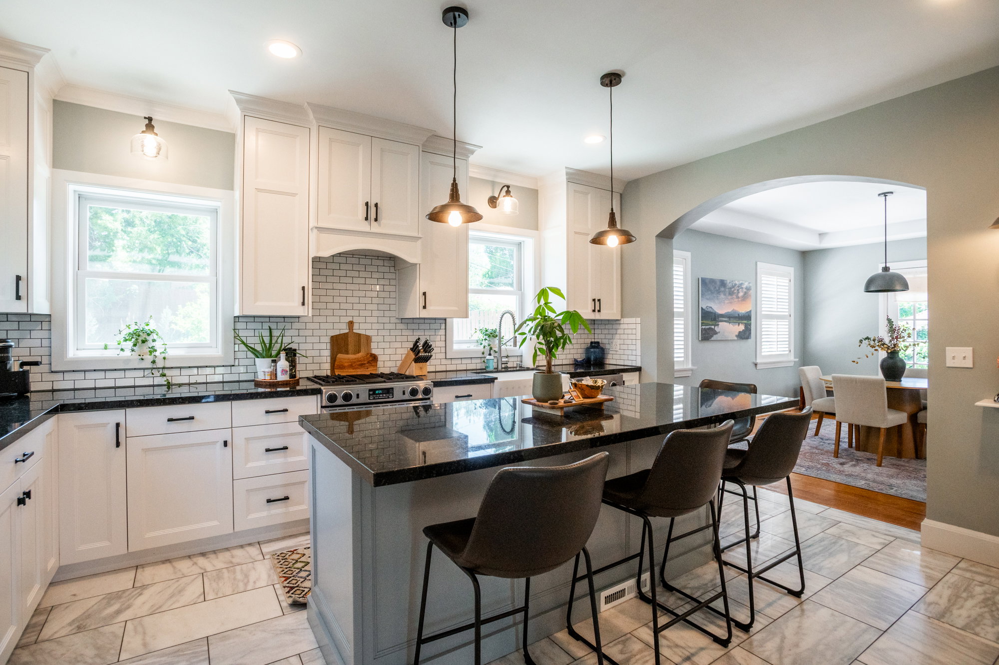 Modern kitchen featuring white shaker cabinetry, dark countertops, a subway tile backsplash, and a central island with pendant lighting