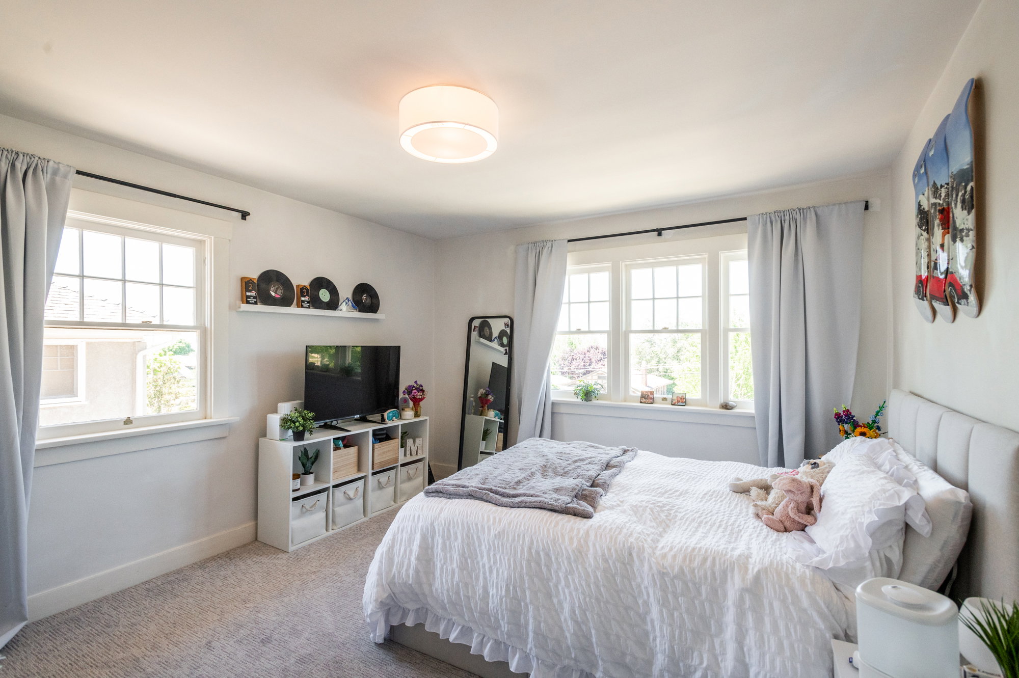 Bedroom featuring a neutral color palette, carpet flooring, a multi-pane window, and a drum-style ceiling light