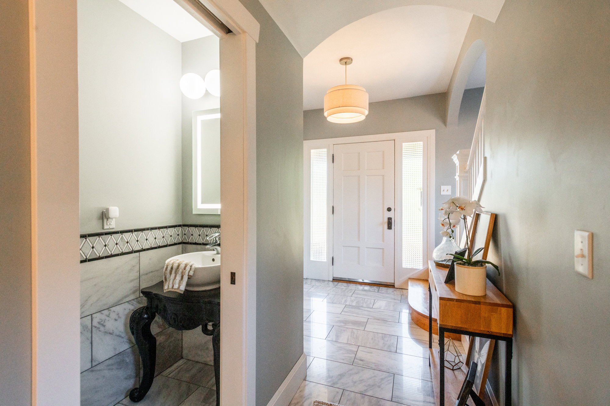 Foyer entrance with a white panel door, side light windows, and overhead drum pendant lighting