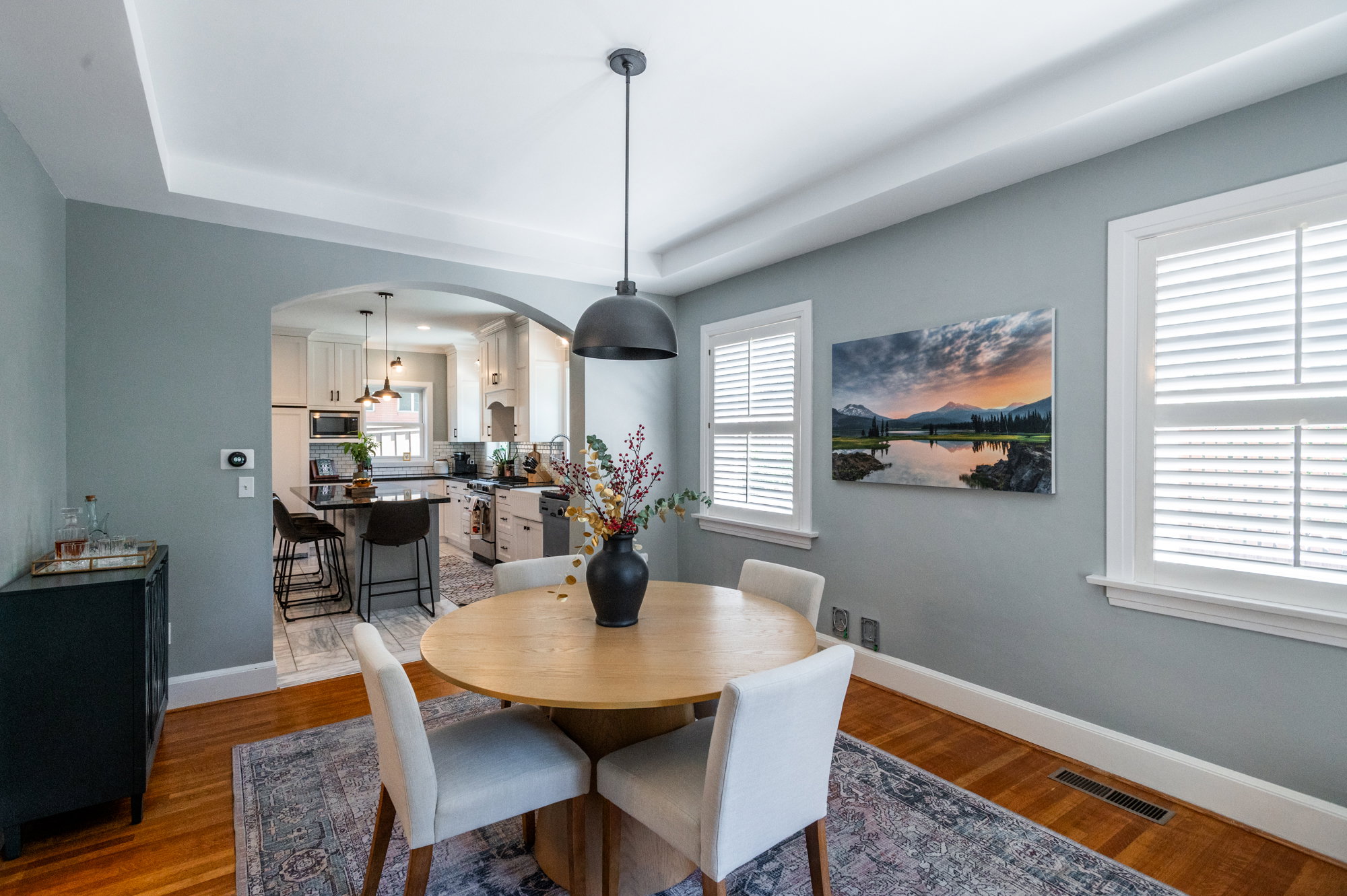 Dining area featuring wood-finish flooring, a tray ceiling, and a modern pendant light fixture