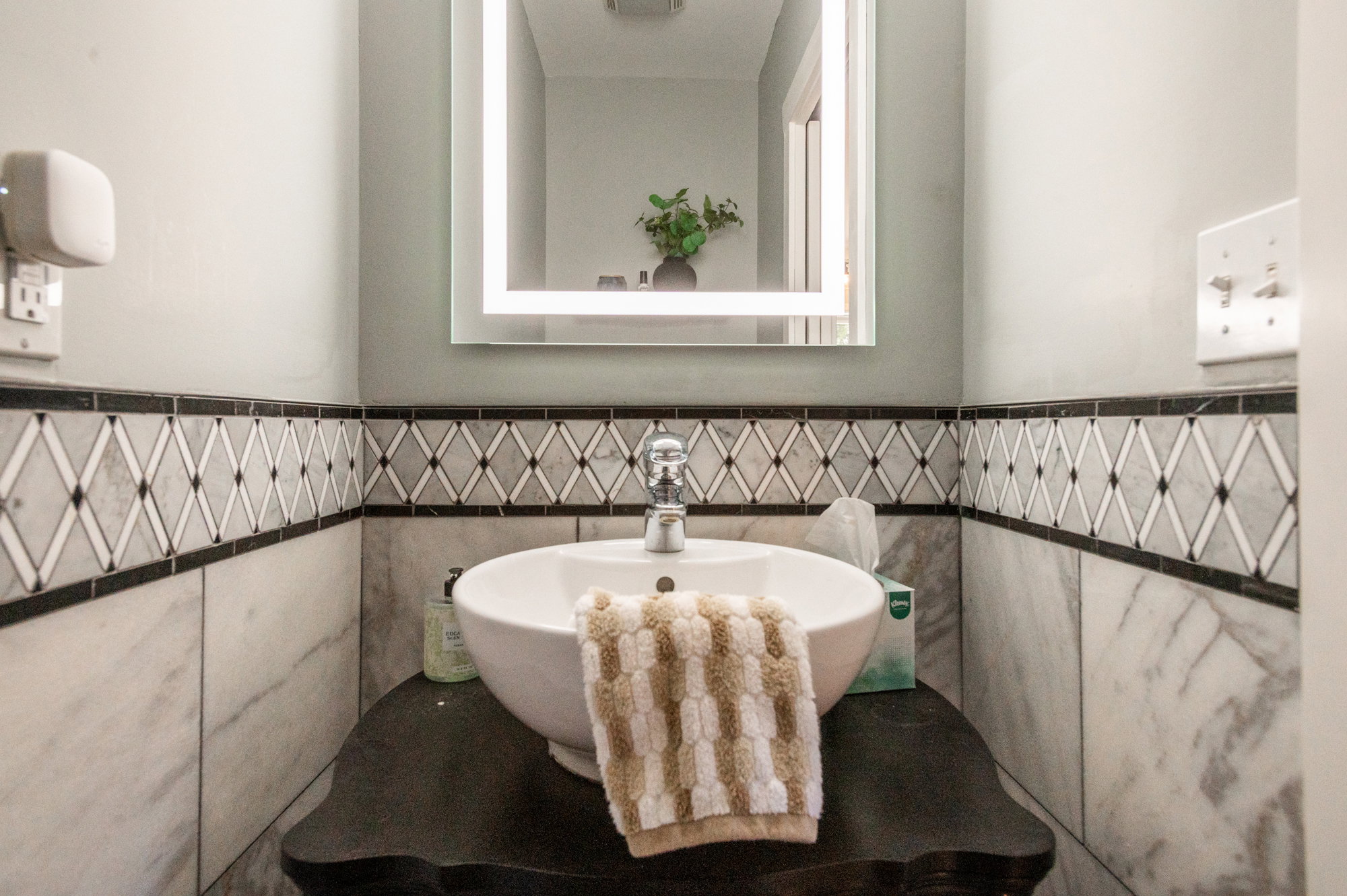 Vanity with vessel sink, wall-mounted faucet, and black countertop