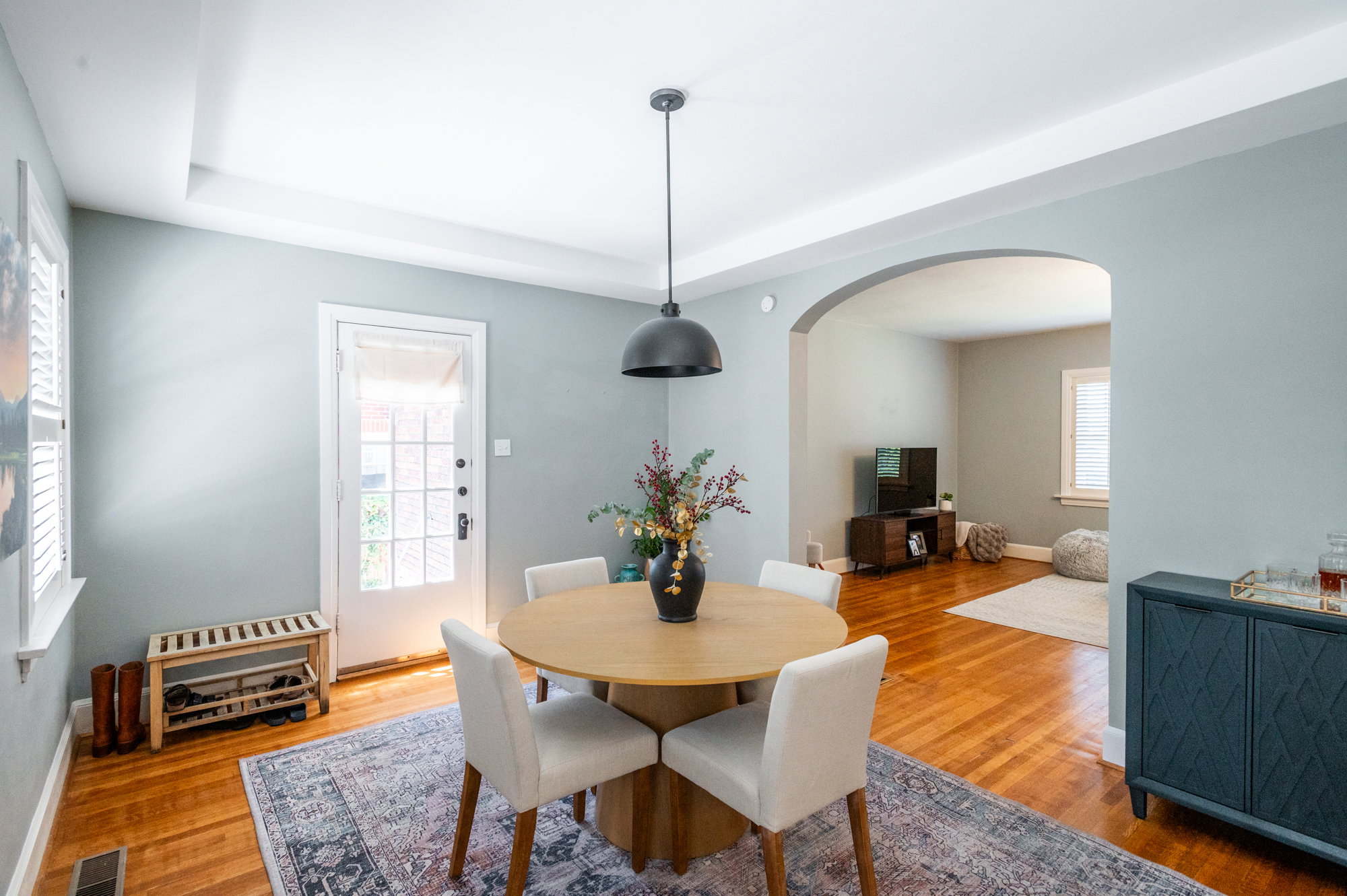 Dining area featuring wood-finish flooring, a tray ceiling, and an arched doorway