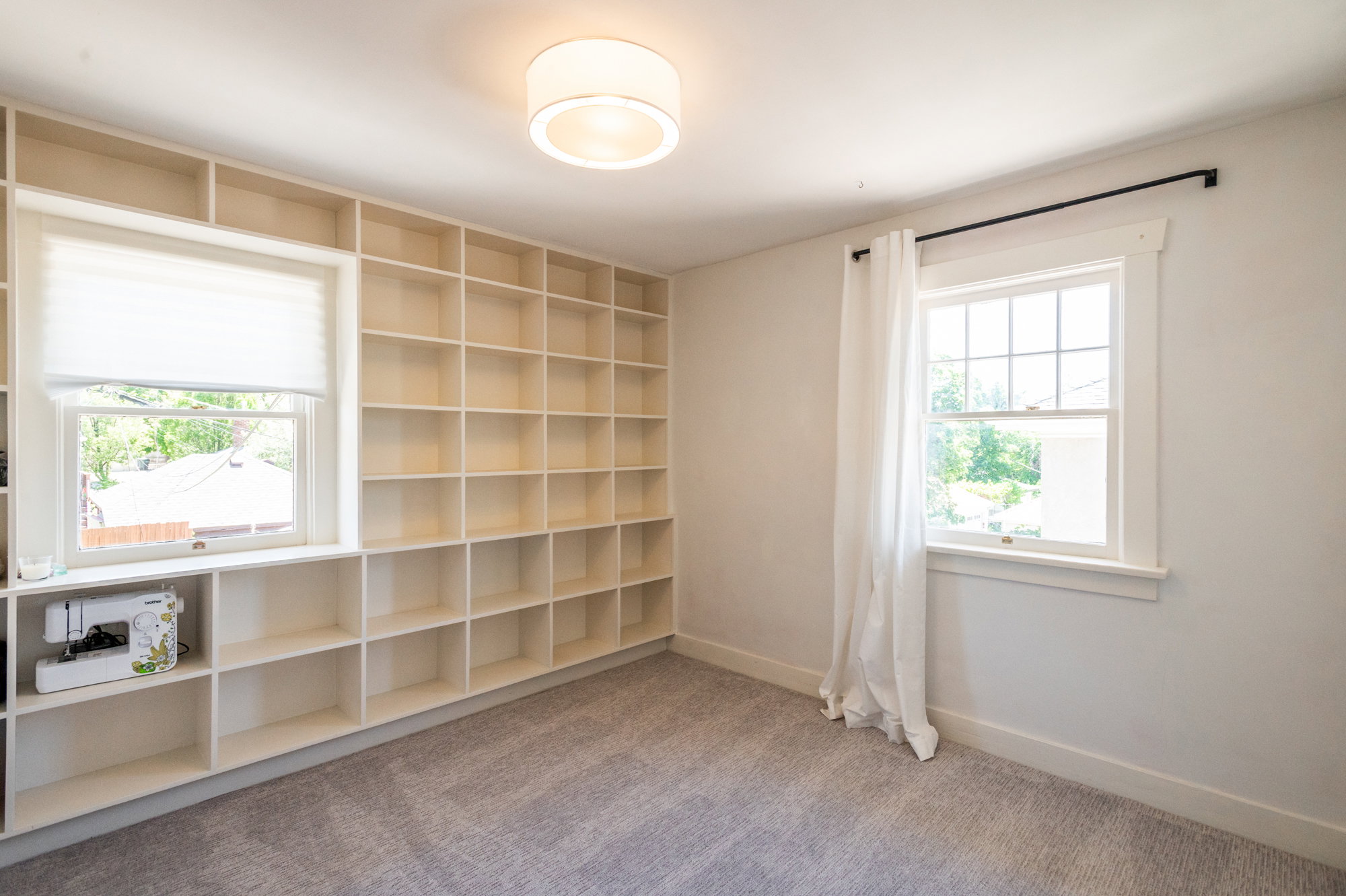 Room featuring extensive built-in shelving, two windows with white trim, and a contemporary flush-mount ceiling light