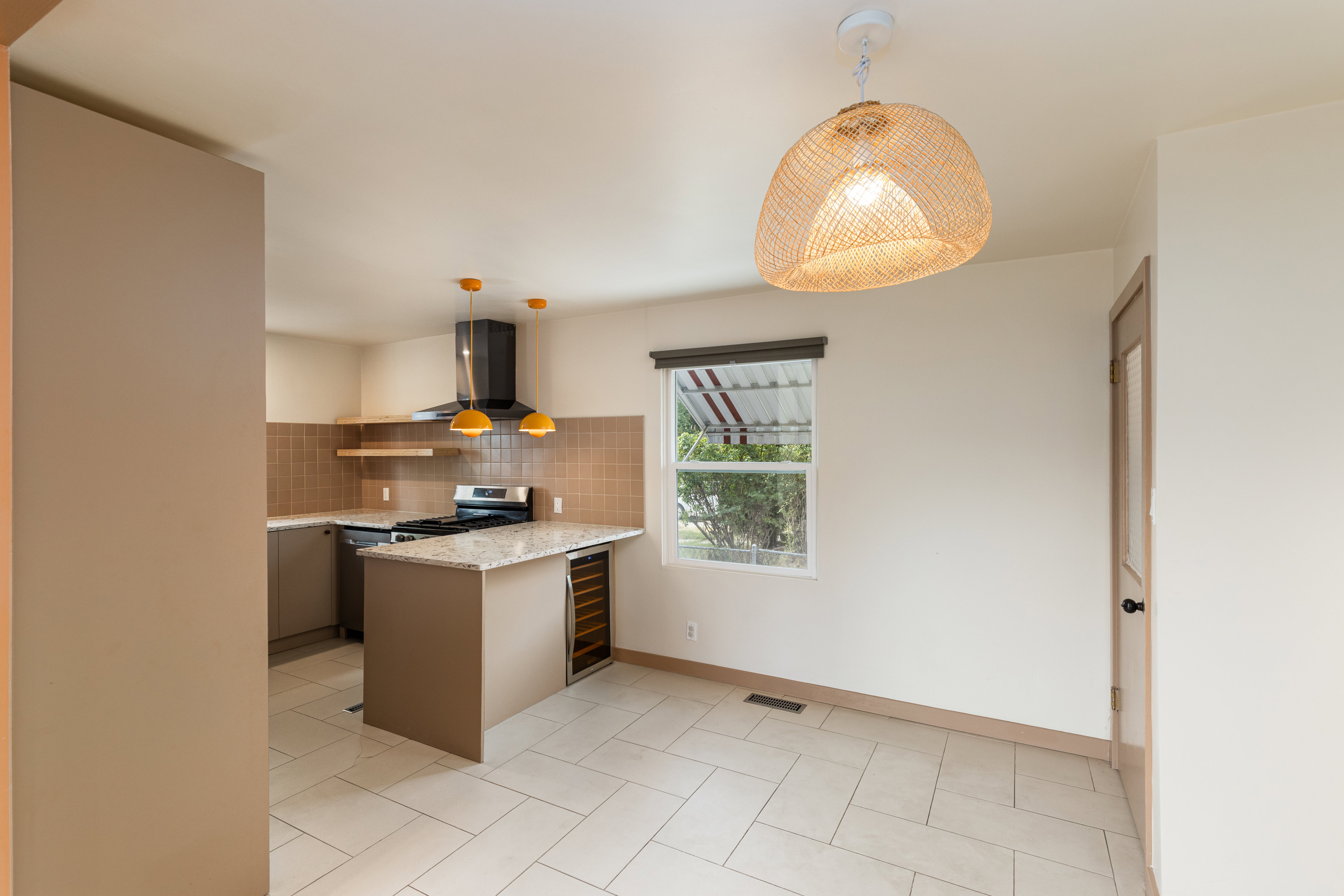 Kitchen featuring a gas range with range hood, built-in dishwasher, and a center island with a beverage refrigerator
