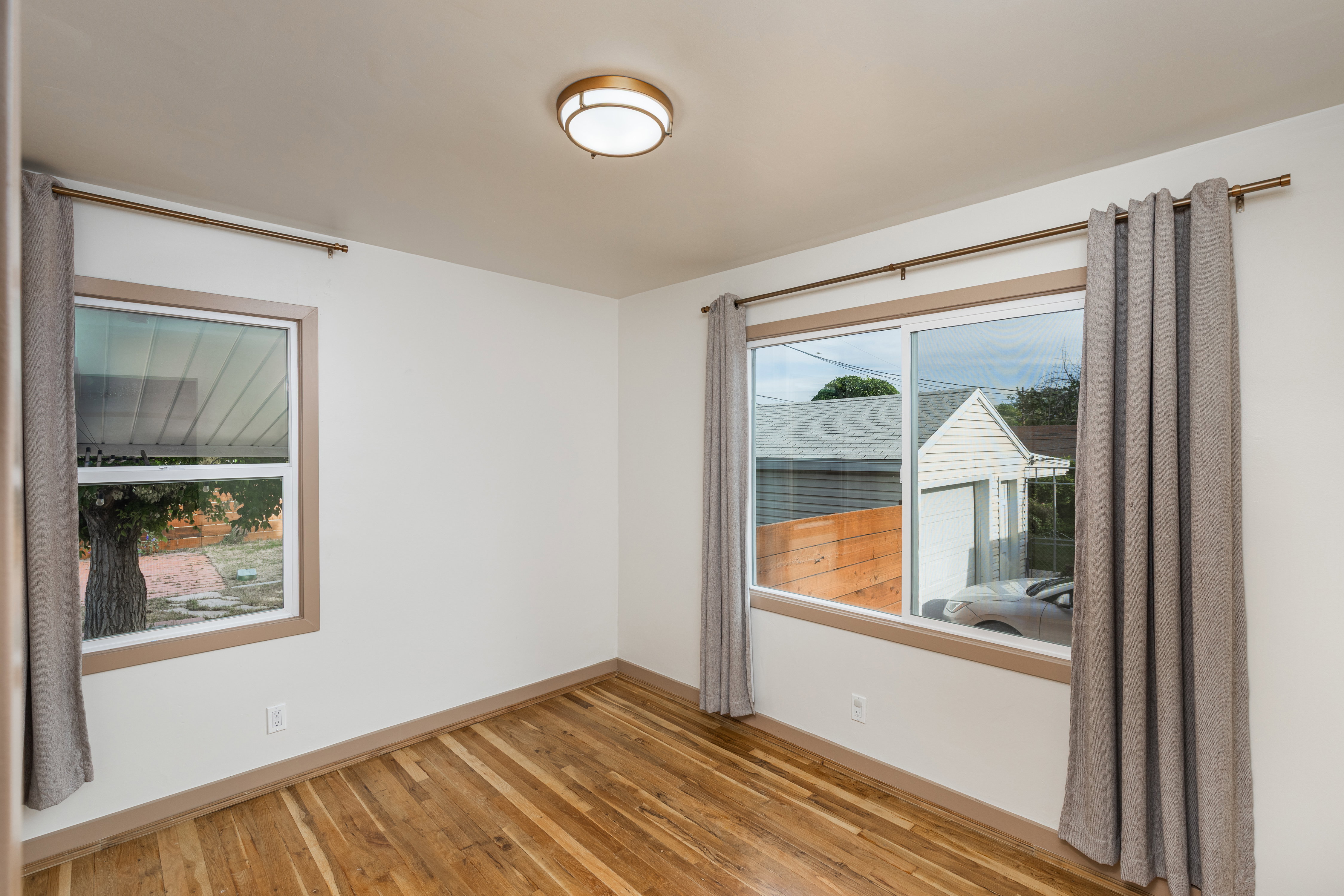 Spacious room featuring wood-finish flooring, white walls, and a contemporary flush-mount ceiling light