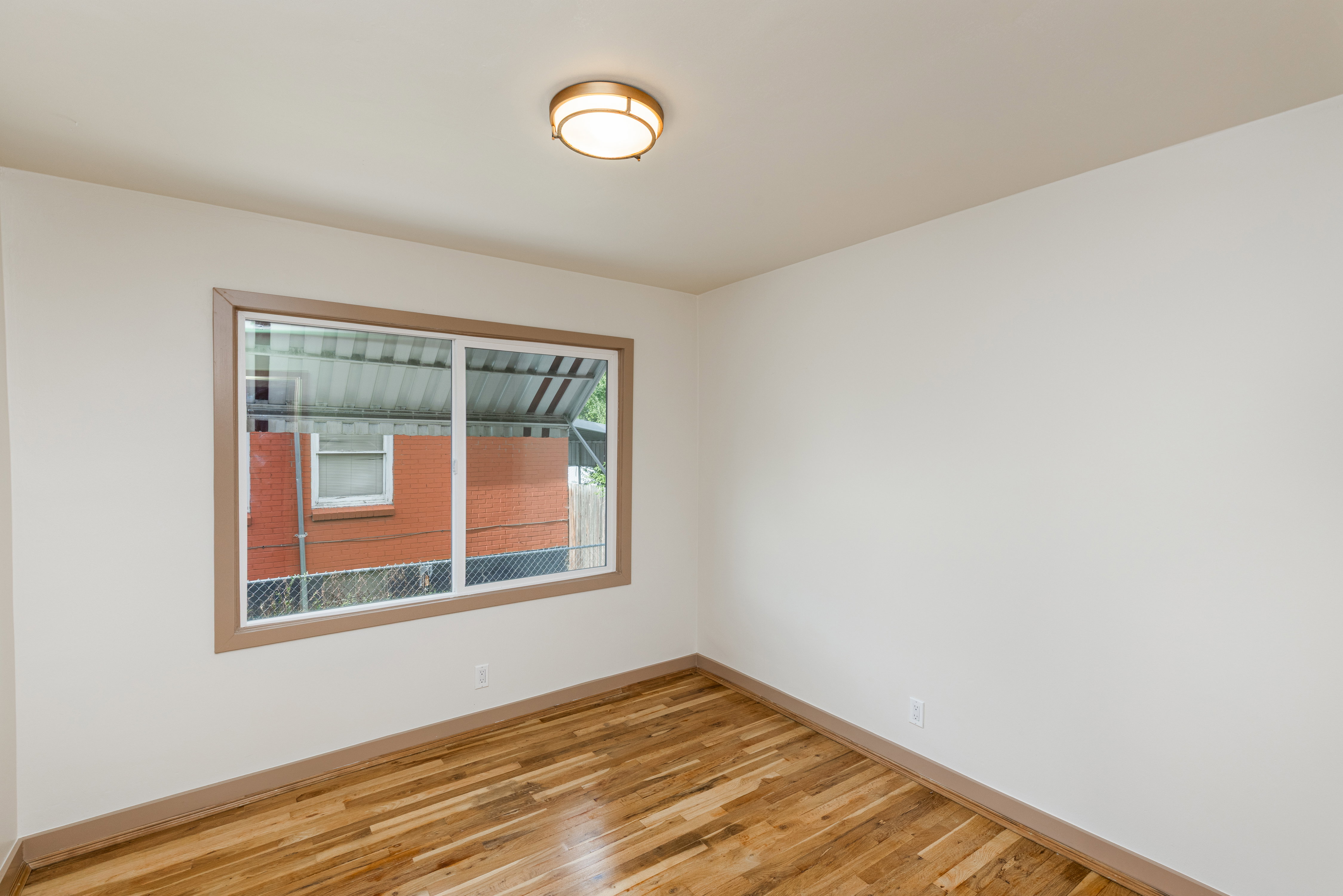 Windowed room with wood-finish flooring and a flush-mount ceiling light