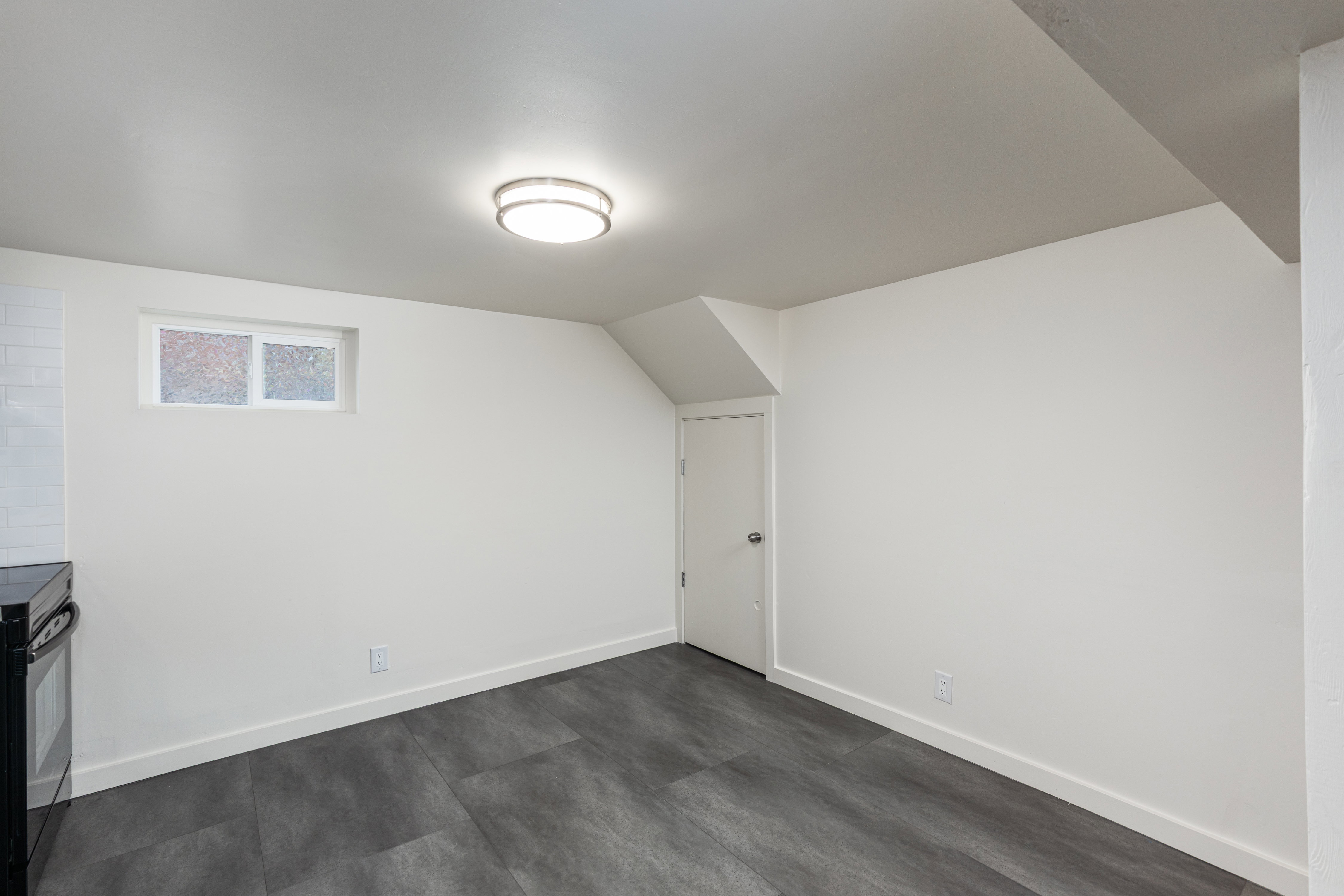 Brightly lit interior space featuring dark wood-finish flooring, white walls, and a white subway tile backsplash