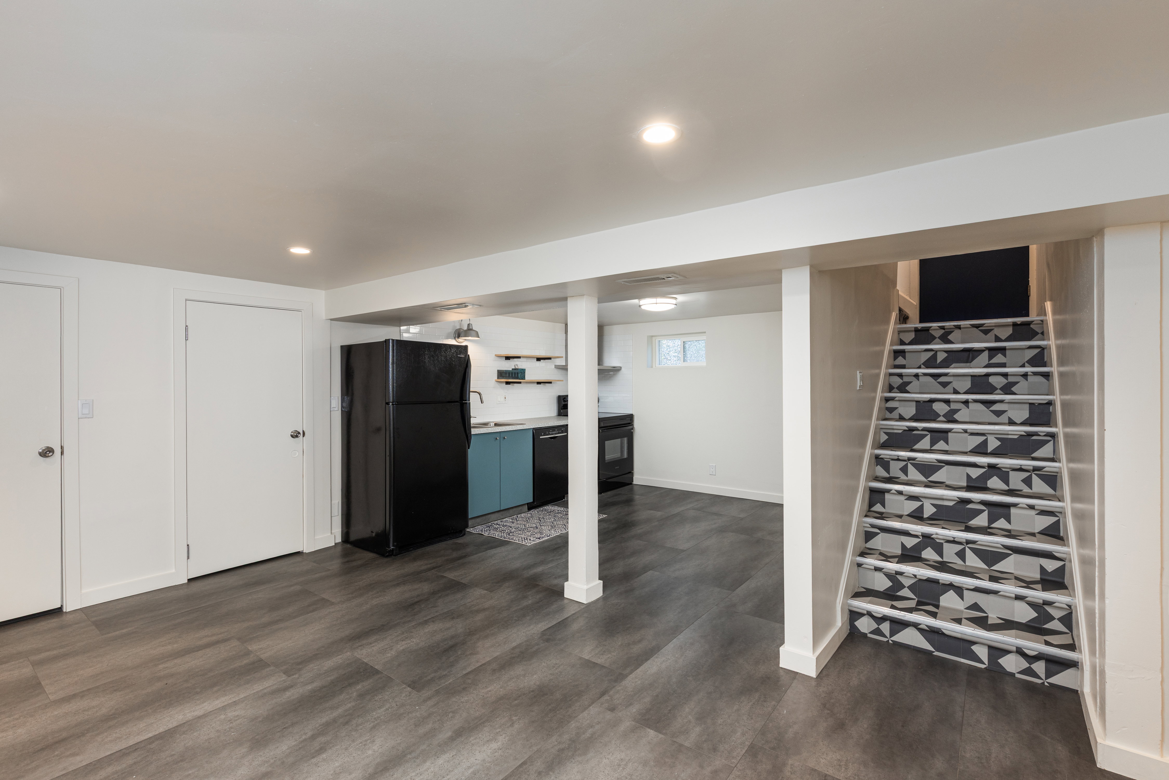 Finished lower level featuring wood-finish flooring, recessed lighting, and a contemporary kitchen area with blue cabinetry